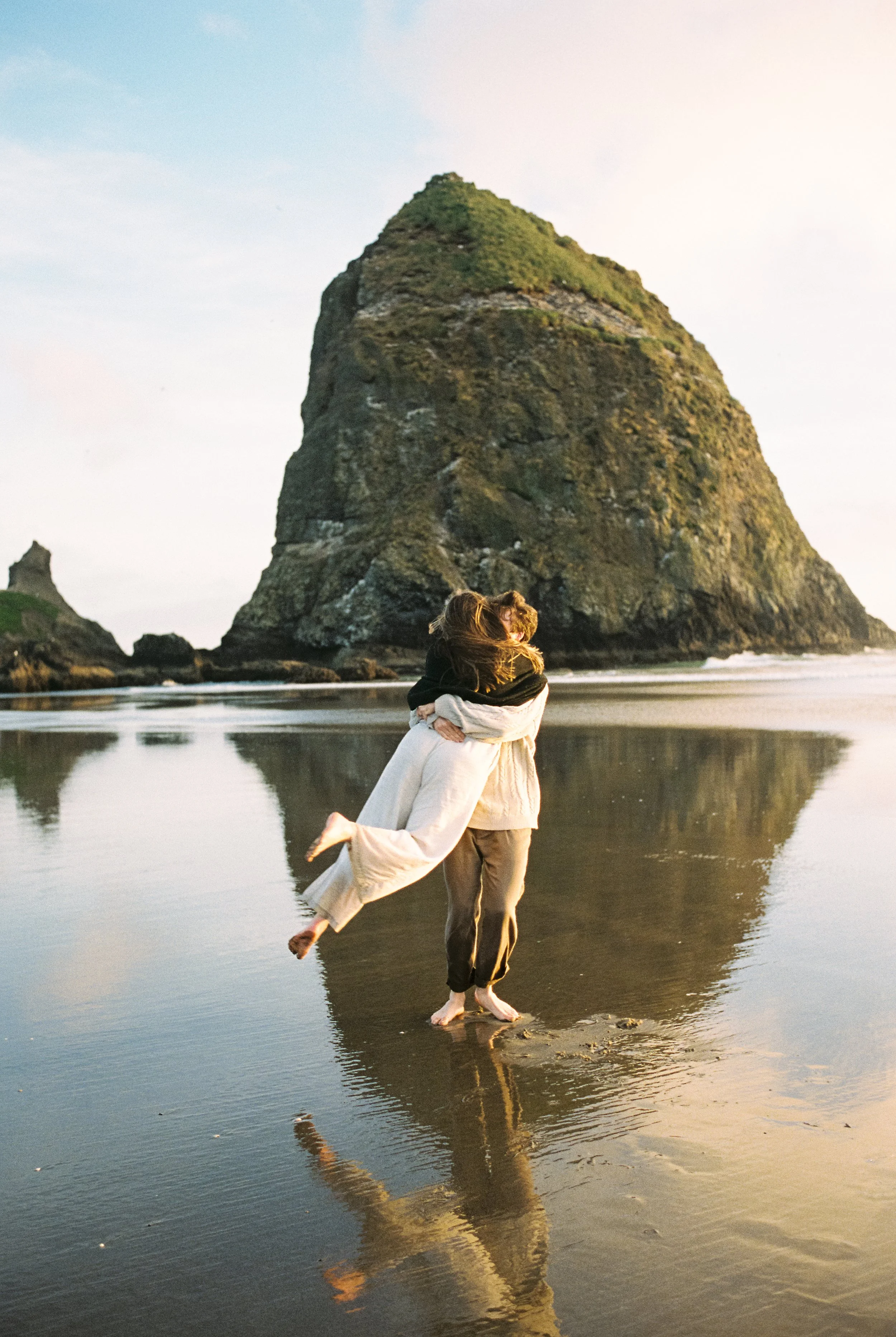 a engagement couple spinning in a circle in the ocean laughing candid on film photography