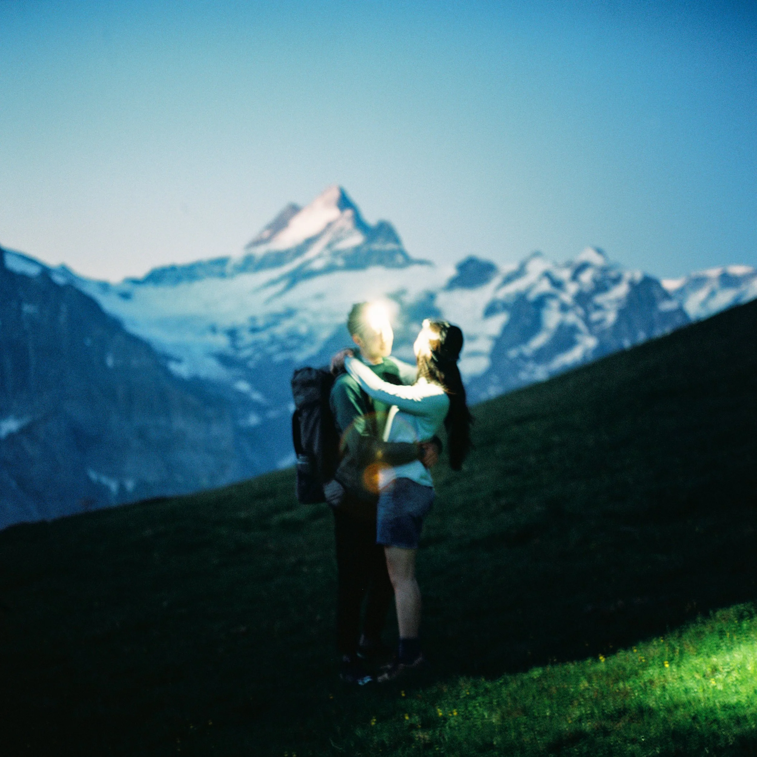 a couple standing at blue hour embracing in front of the swiss alps