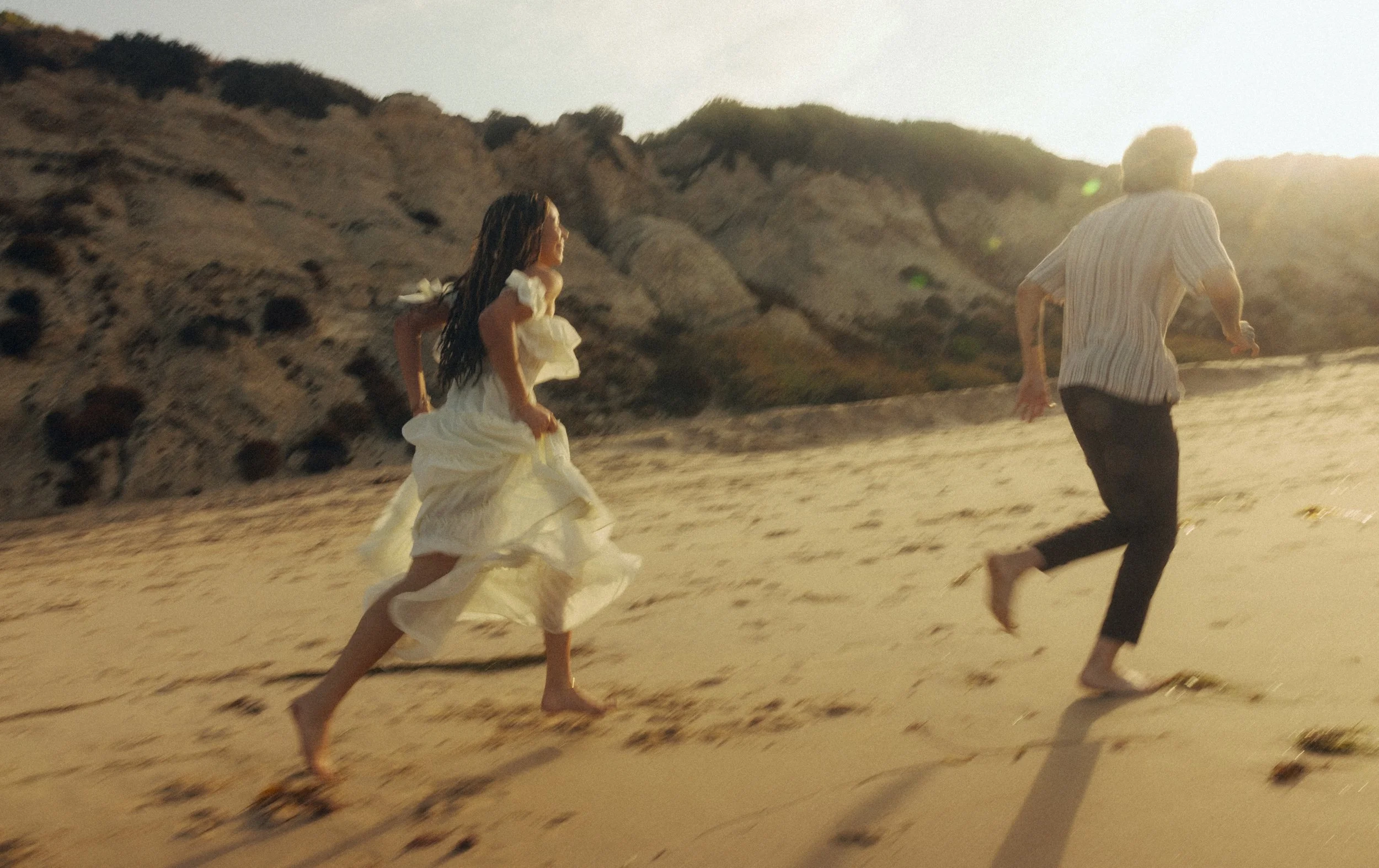 a bride and groom running down the oregon coast at sunrise