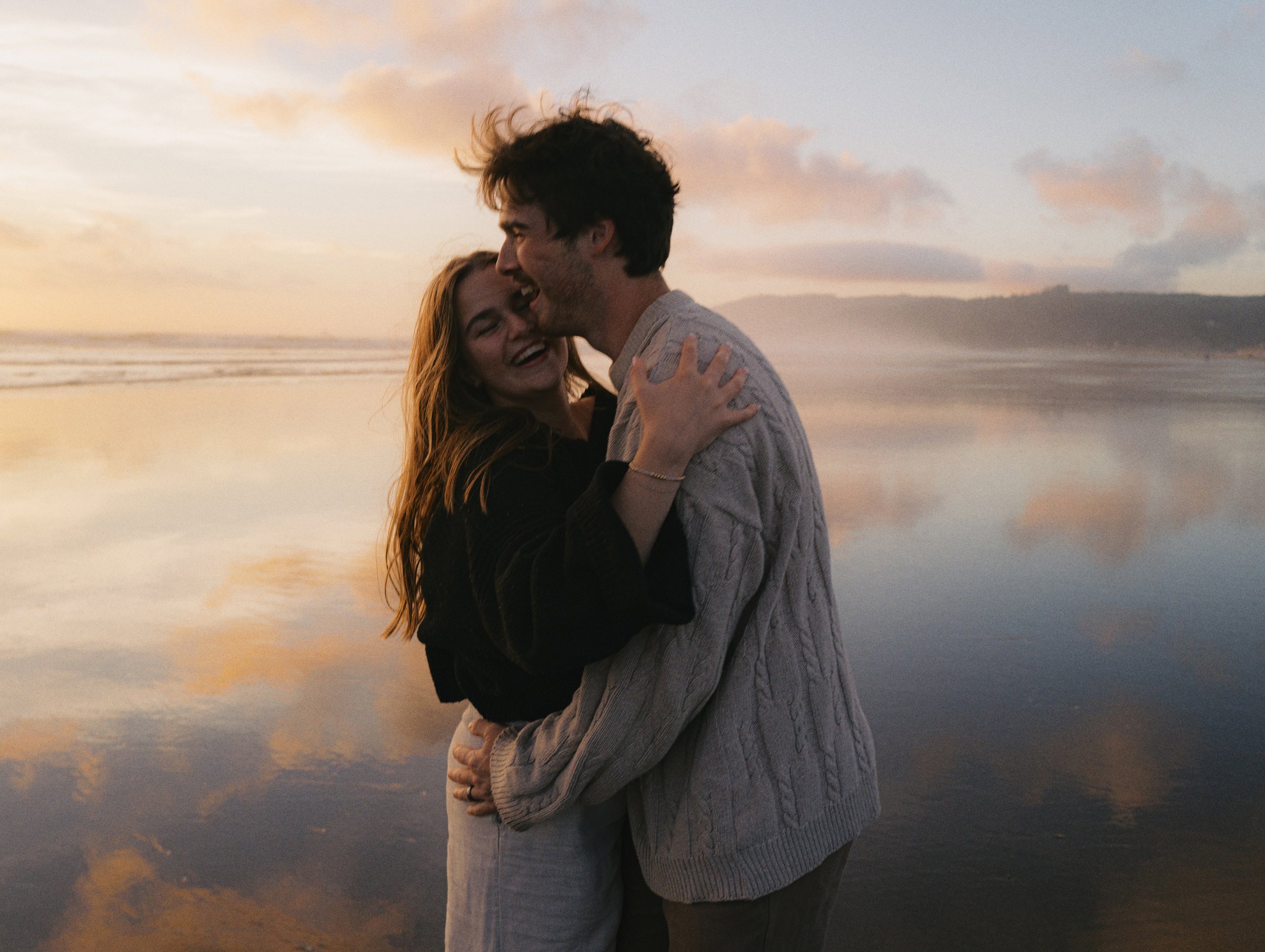 couple holding each other laughing candid, on film on the oregon coast