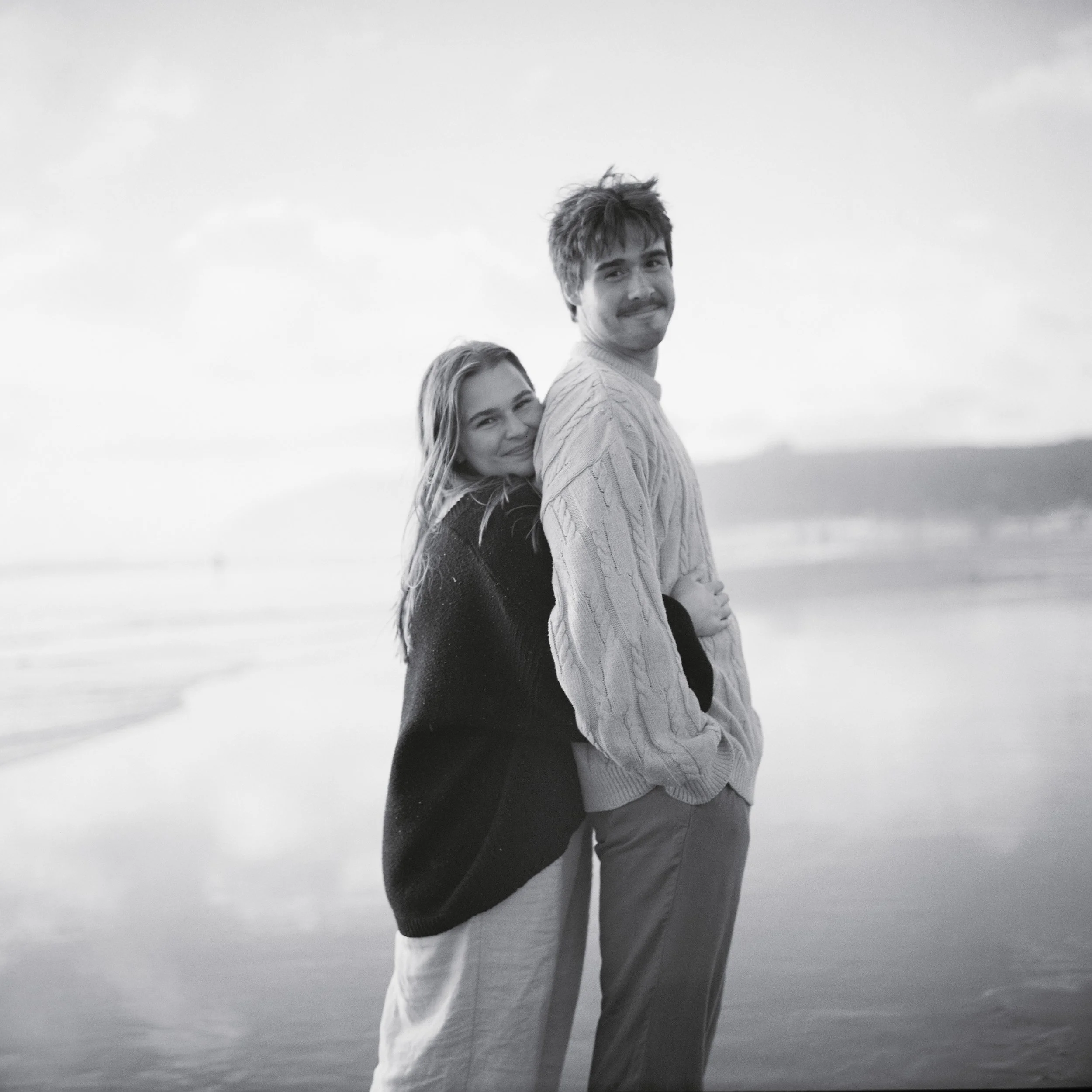a engagement couple holding posed from behind hands on black and white film