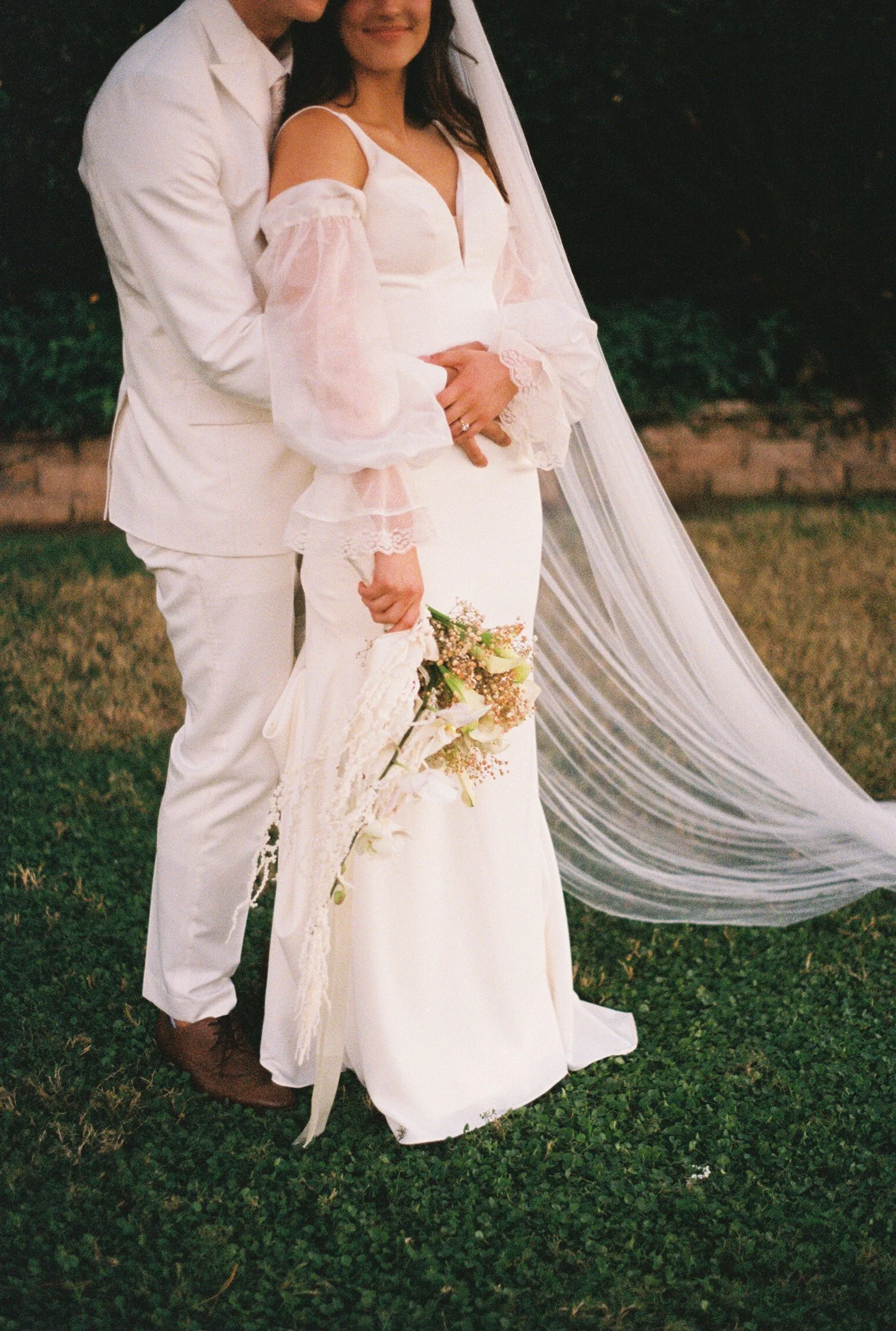 bride and groom with a bouquet of florals, standing together