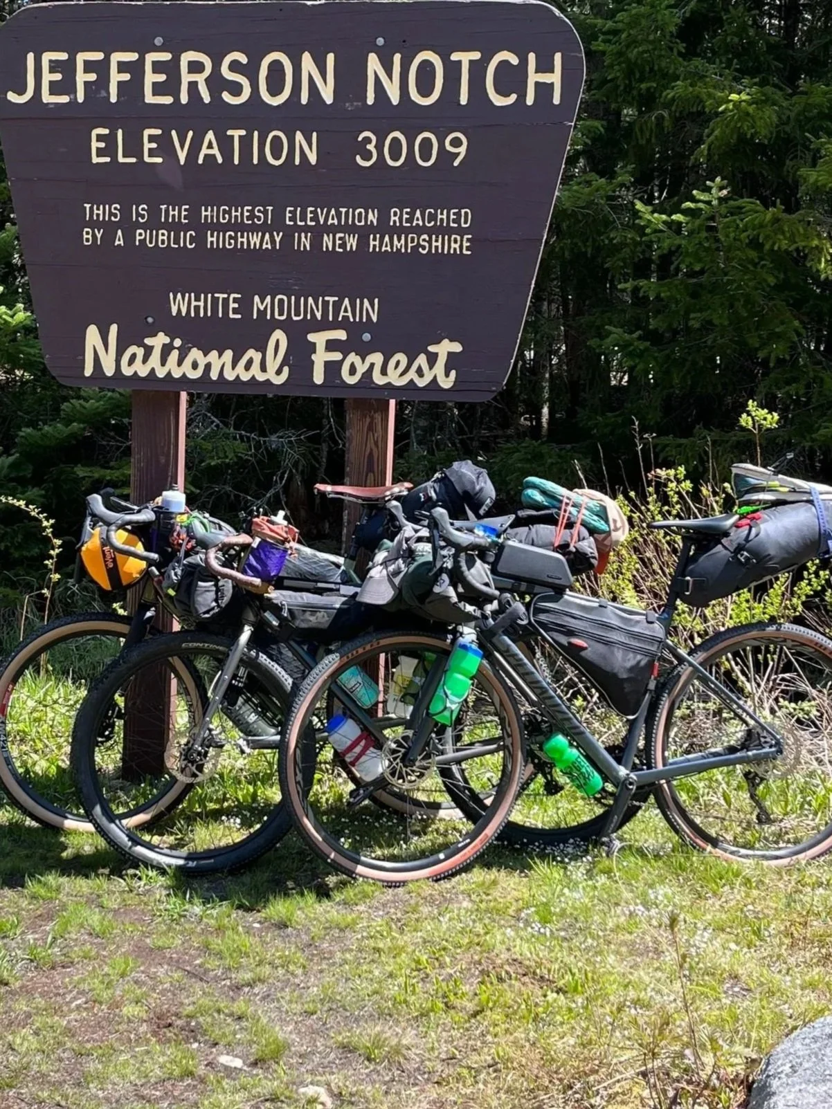 Two bicycles loaded with gear parked beneath a sign for Jefferson Notch, which has an elevation of 3009 feet, located in White Mountain National Forest.