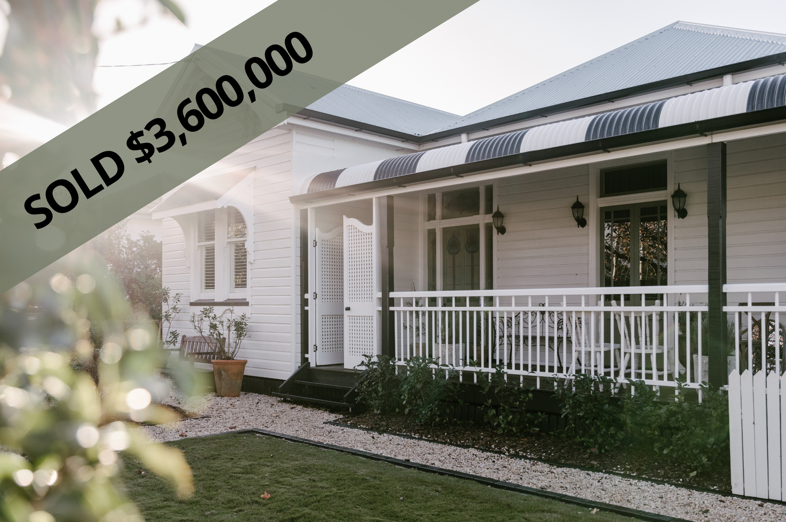 White house with black trim on porch, with a white railing, potted plants, and outdoor furniture, marked as sold for $3,600,000.
