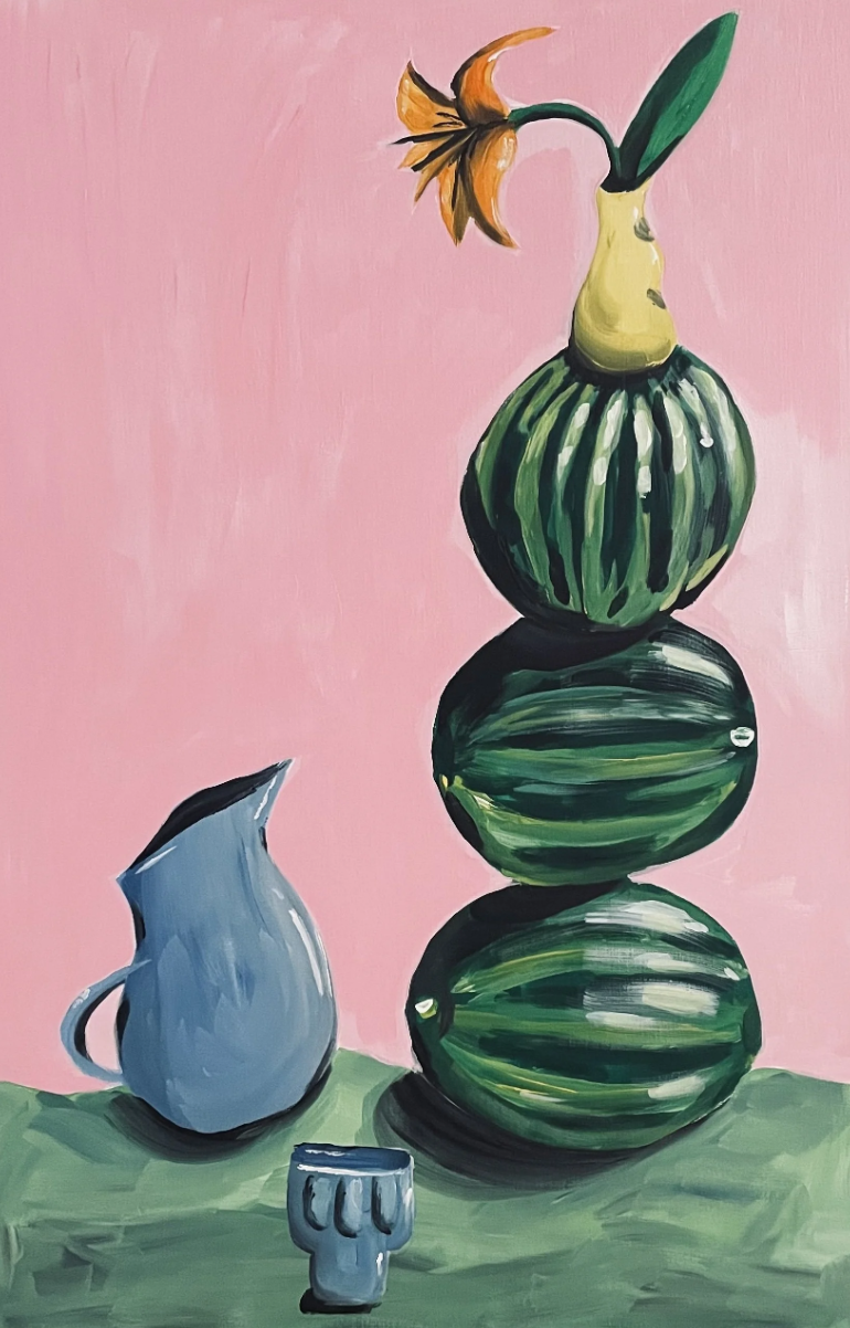 A still life painting featuring a pink background and green grassy surface. A stack of three watermelons is positioned vertically, with the top watermelon topped by a watermelon rind vase holding a wilted orange flower. To the left of the watermelons, there is a blue pitcher with a handle and spout, and a small blue cup or mug nearby.