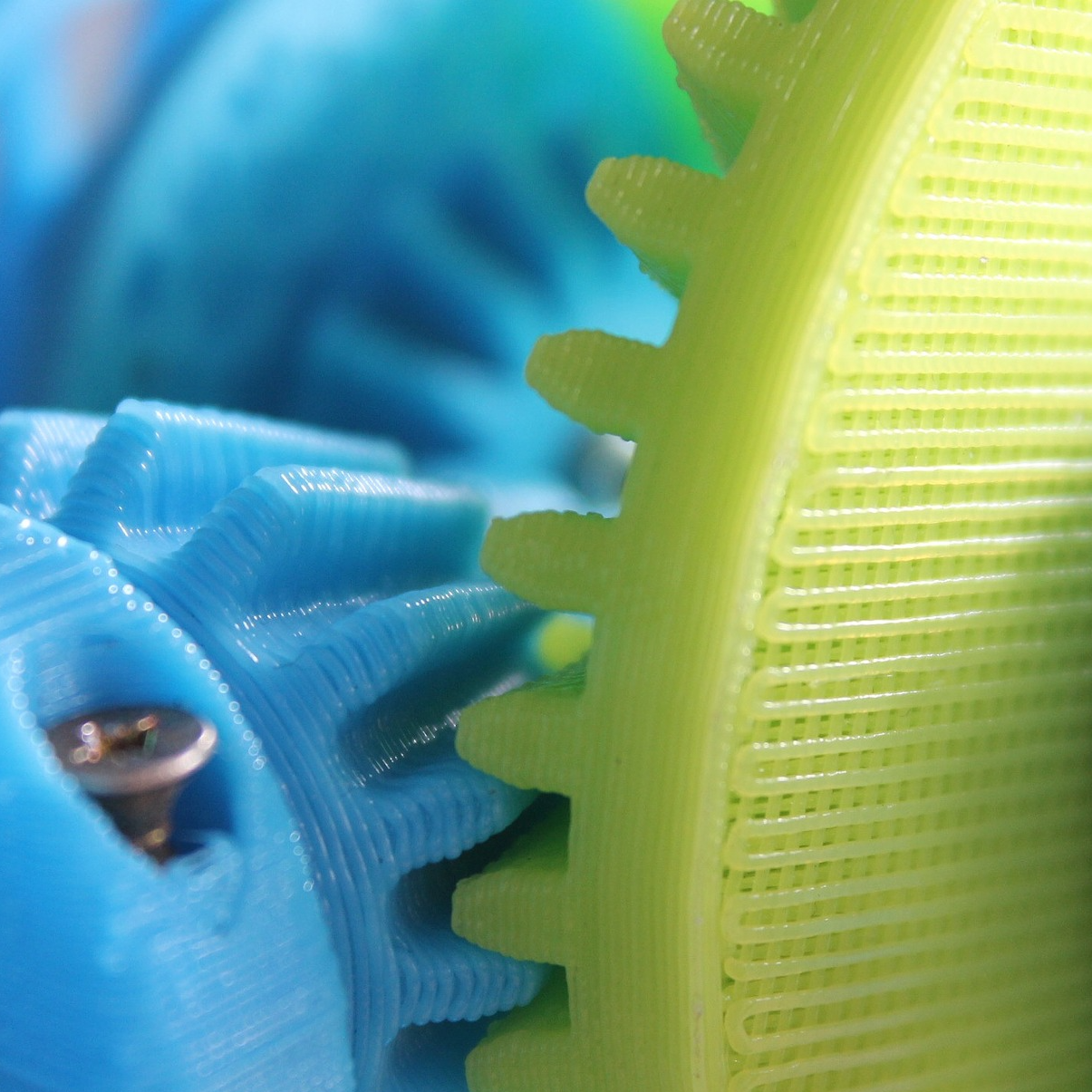 Close-up of green and blue plastic gears with interlocking teeth.