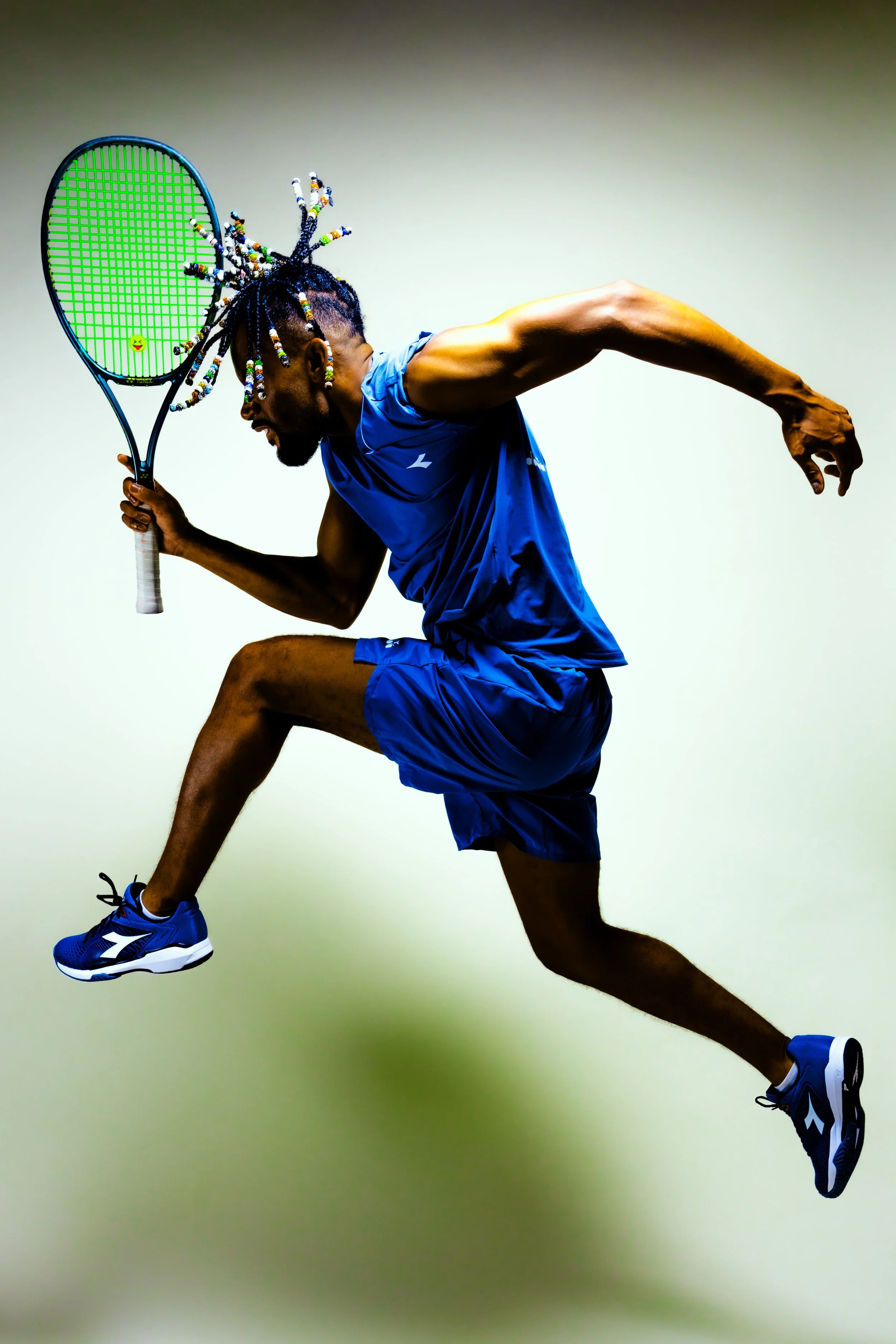 An athlete in blue sportswear jumping with a tennis racket in hand.