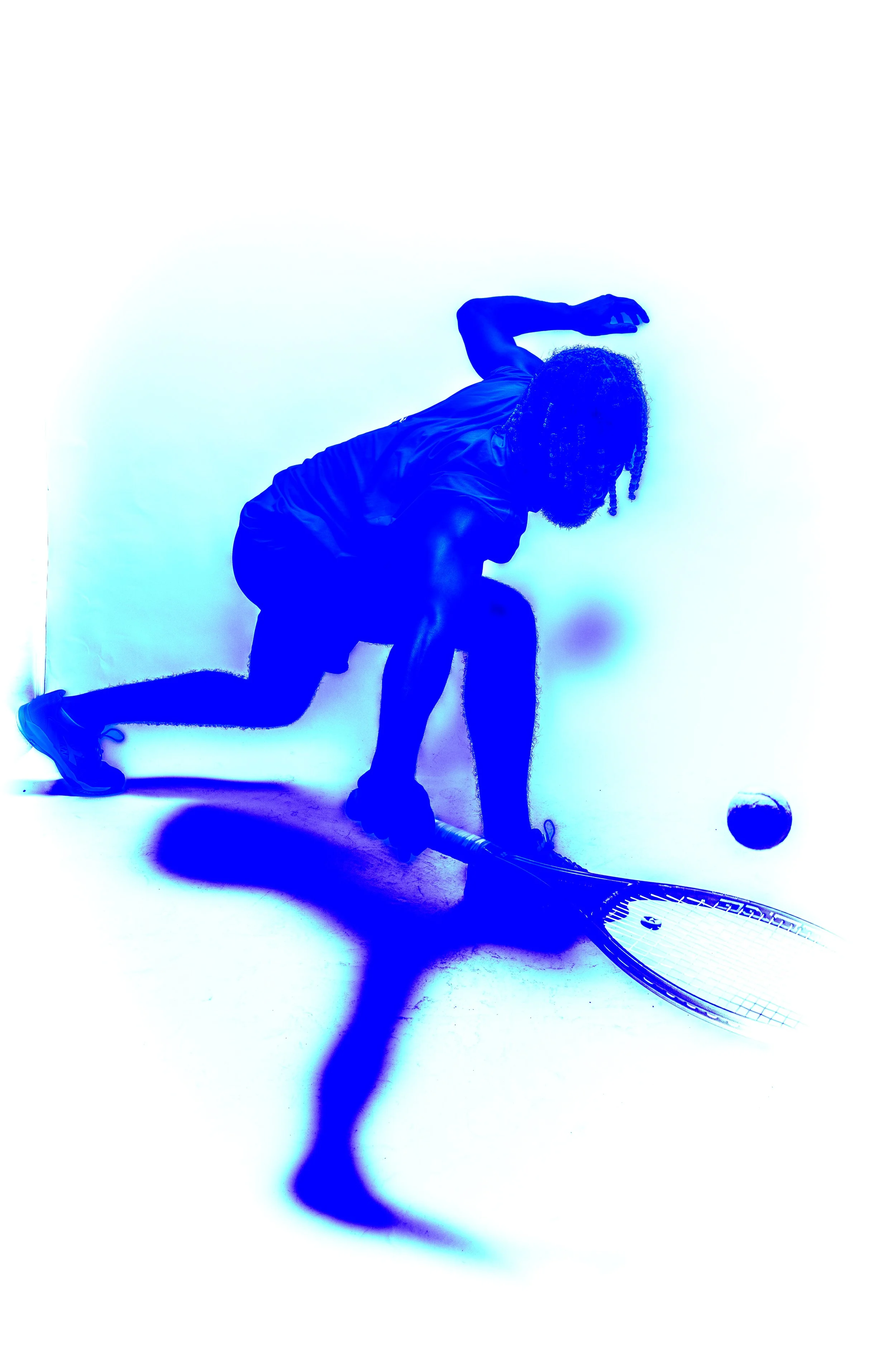 Person with curly hair in sports attire playing hockey, positioned low to the ground, reaching for a puck with a hockey stick, against a plain background.