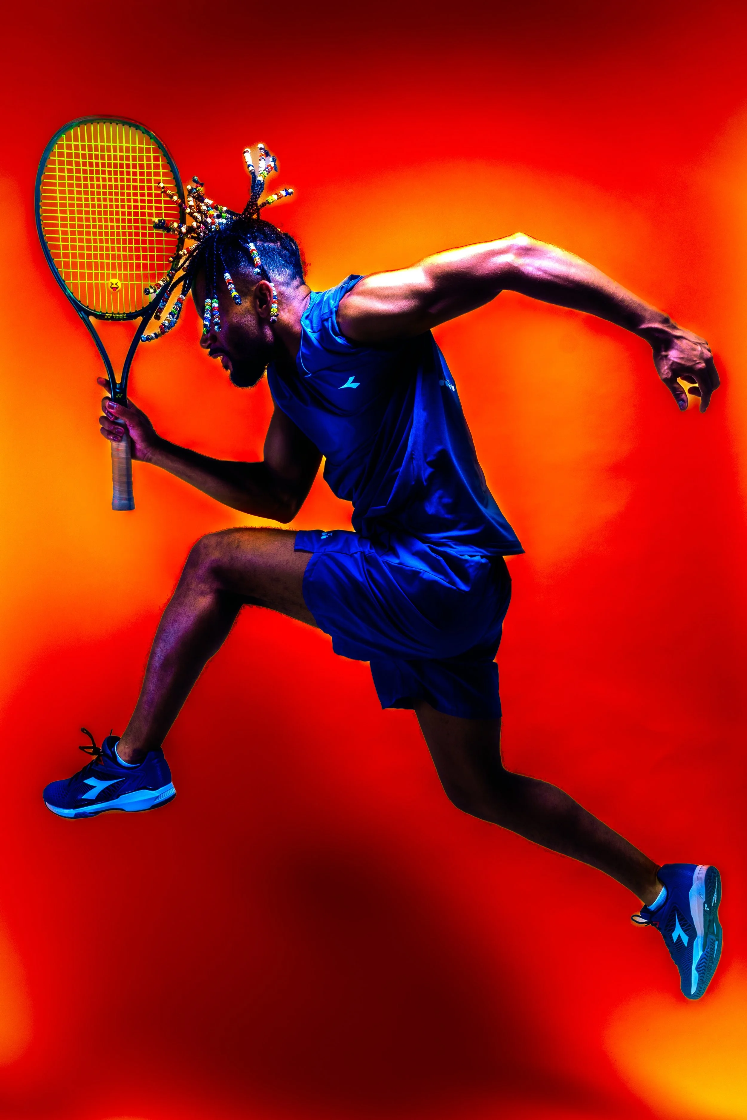 An athlete in a blue sports outfit holding a tennis racket, running with one knee raised, against a vibrant orange background.