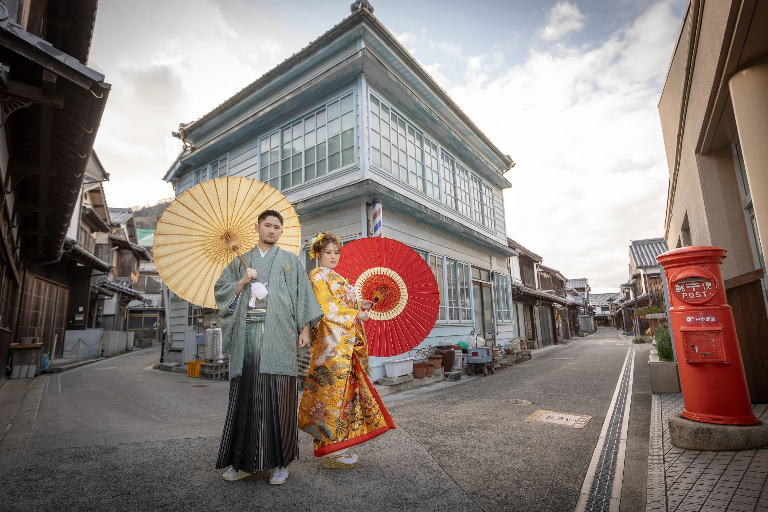 ロケ撮影イメージ｜御手洗町並み保存地区｜和装の新郎新婦が赤と白の和傘を持ちながら路地に立っている。
