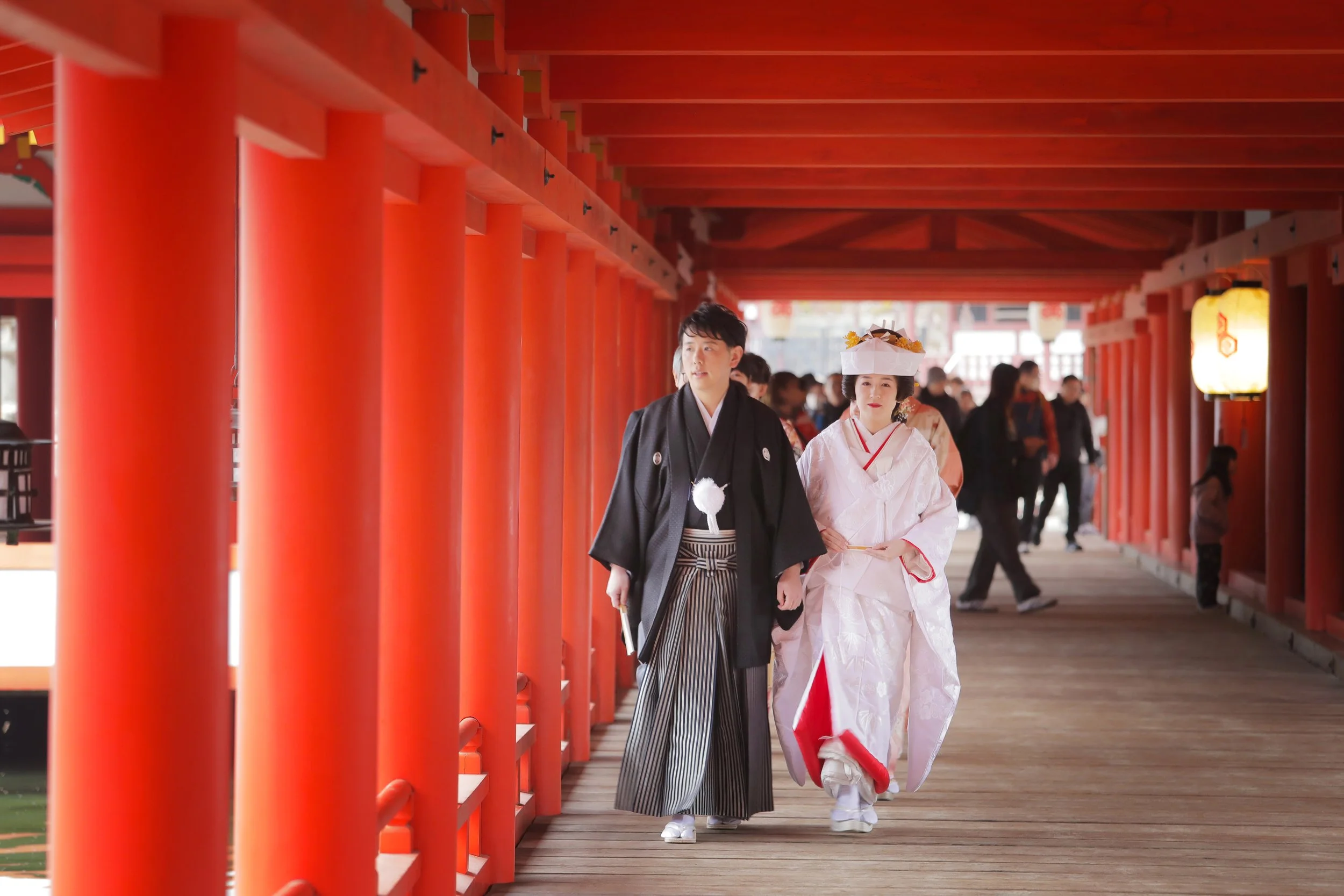 嚴島神社の朱色の回廊を進む新郎新婦