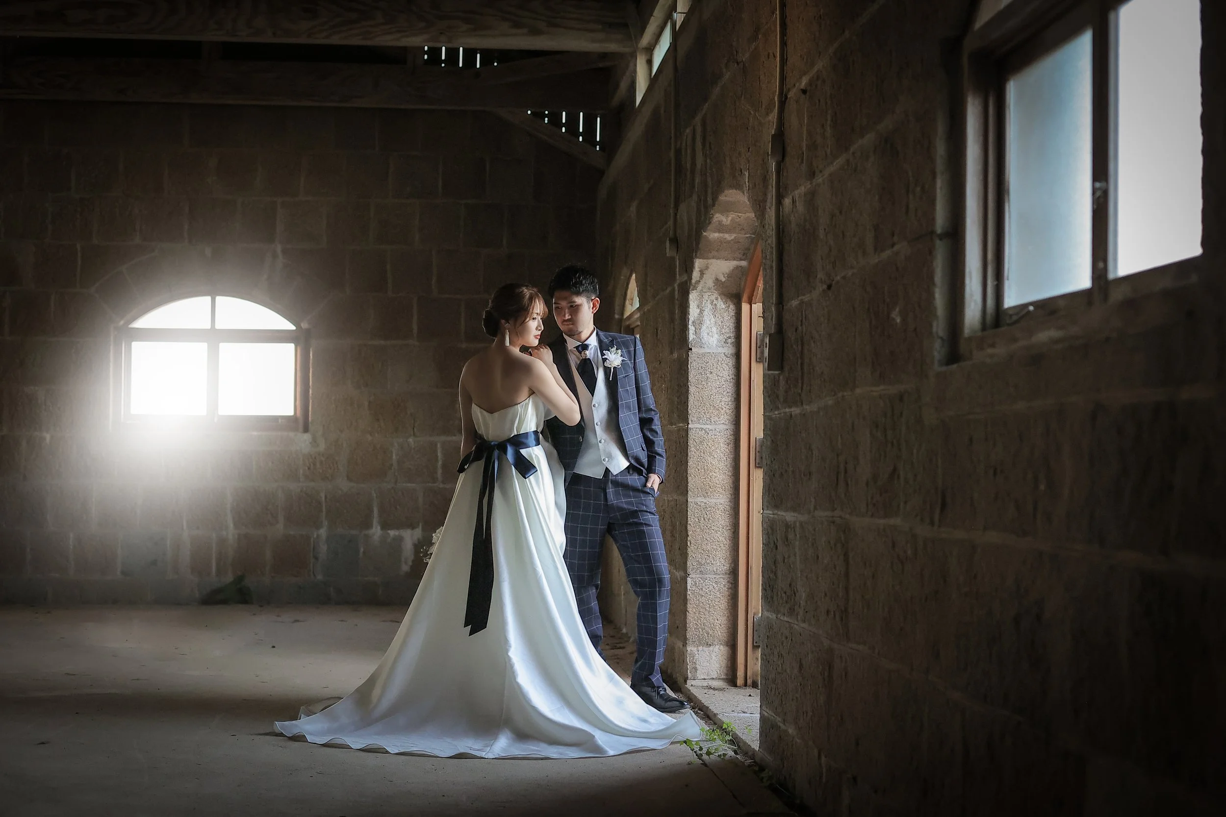 ロケ撮影イメージ | 江田島 三高山砲台跡 | 古いレンガの建物の中でウェディングドレスとタキシードを着たカップルが向き合っている。
