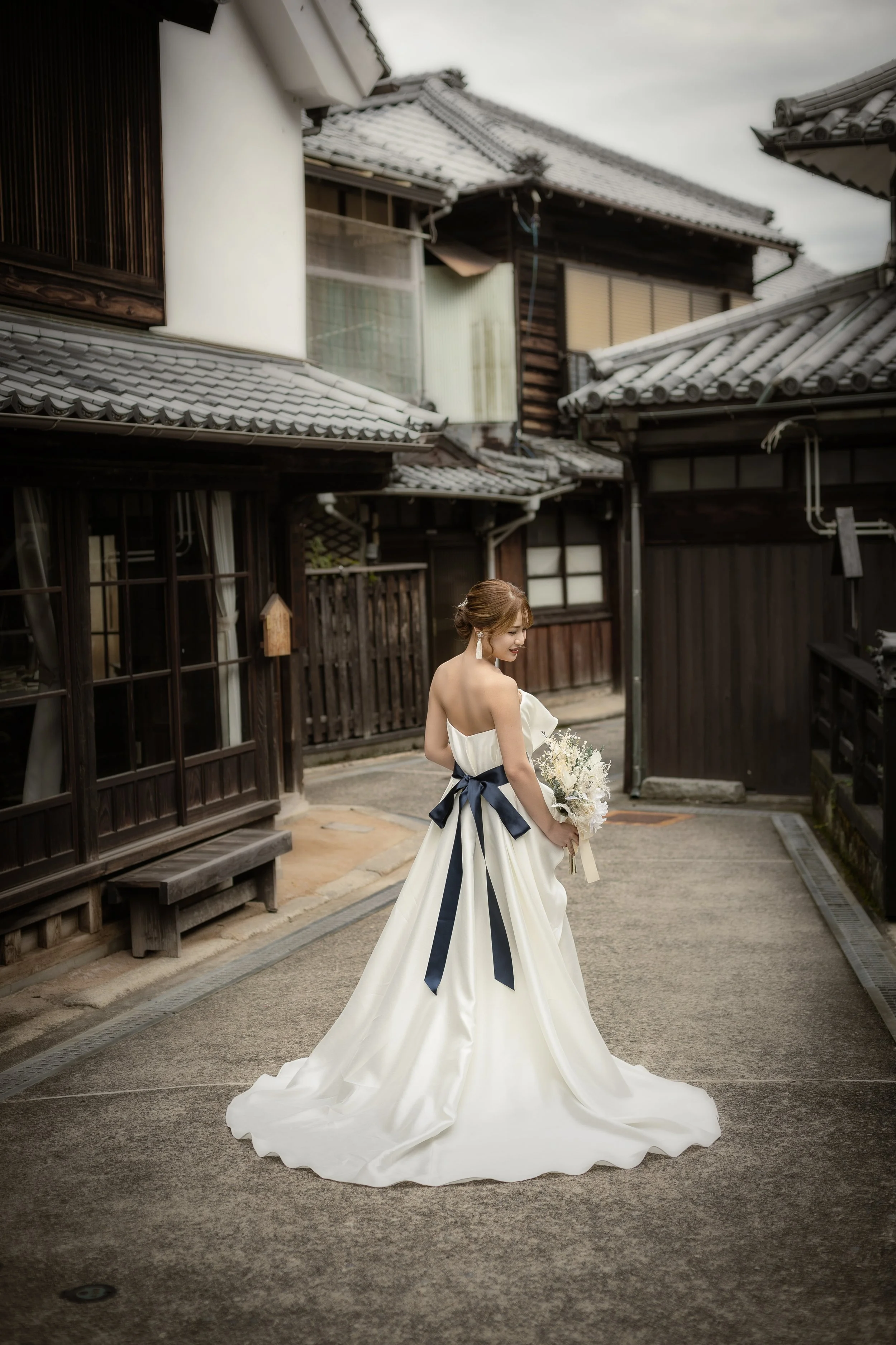 ロケ撮影イメージ | 御手洗町並み保存地区 | 和風の街並みの中にいる、ウェディングドレスを着た女性が花束を持っている場面
