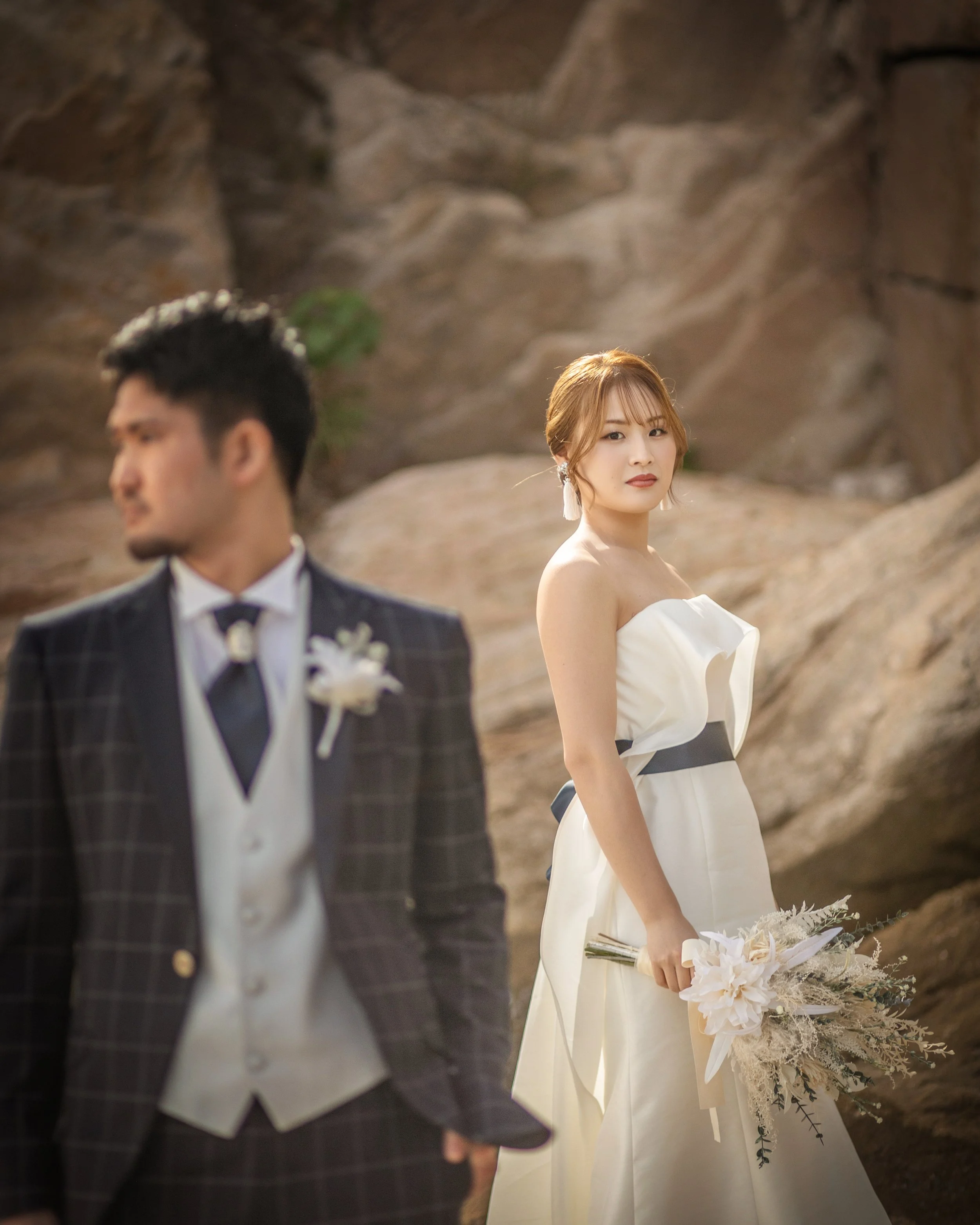 TOPページ　呉エリアキャッチ画像｜新婦が花束を持ち、新郎は手前にいる。背景は岩山のような自然の風景。