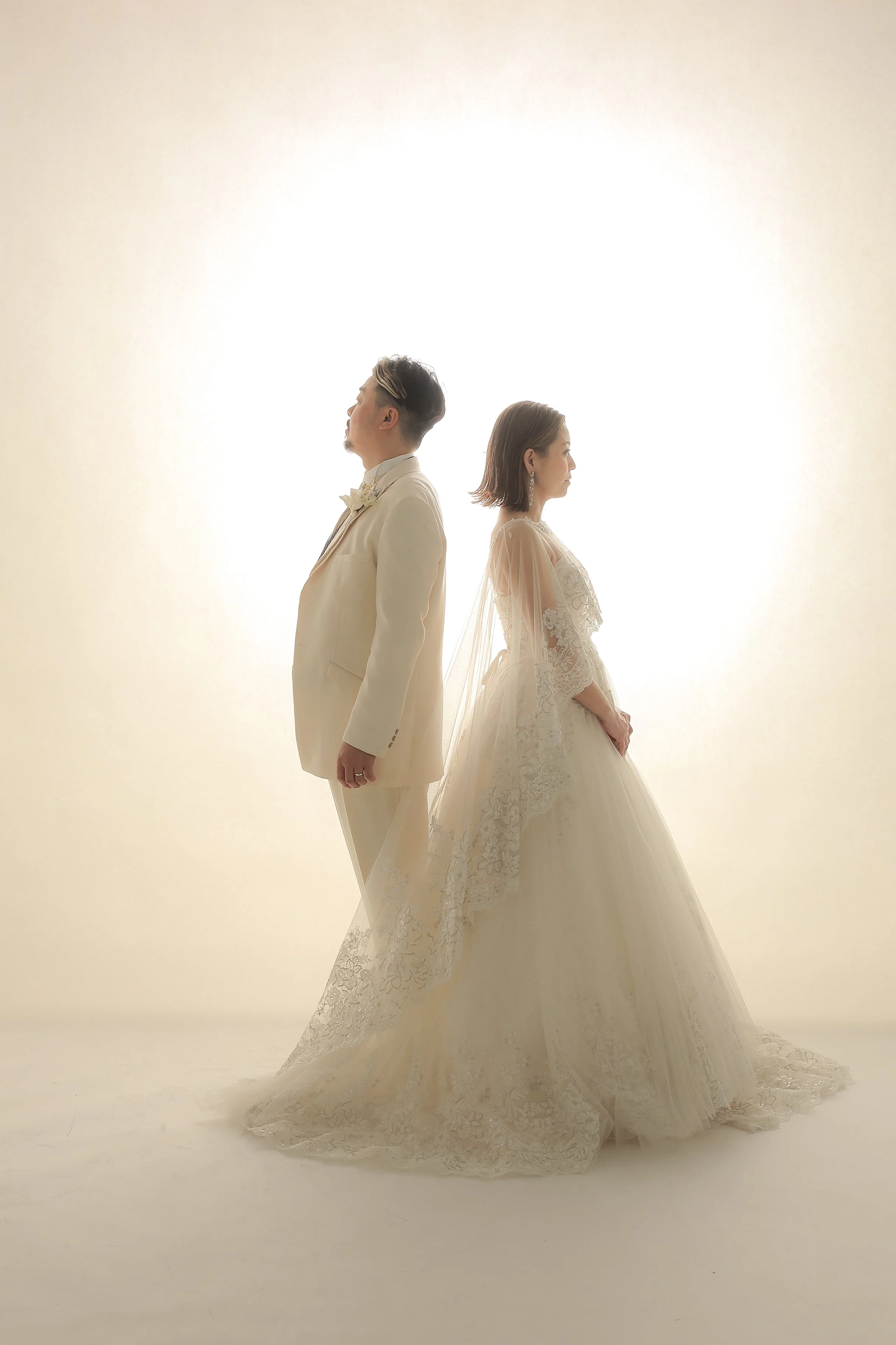 結婚式の衣装を着た男女が背中合わせに立つ写真。
