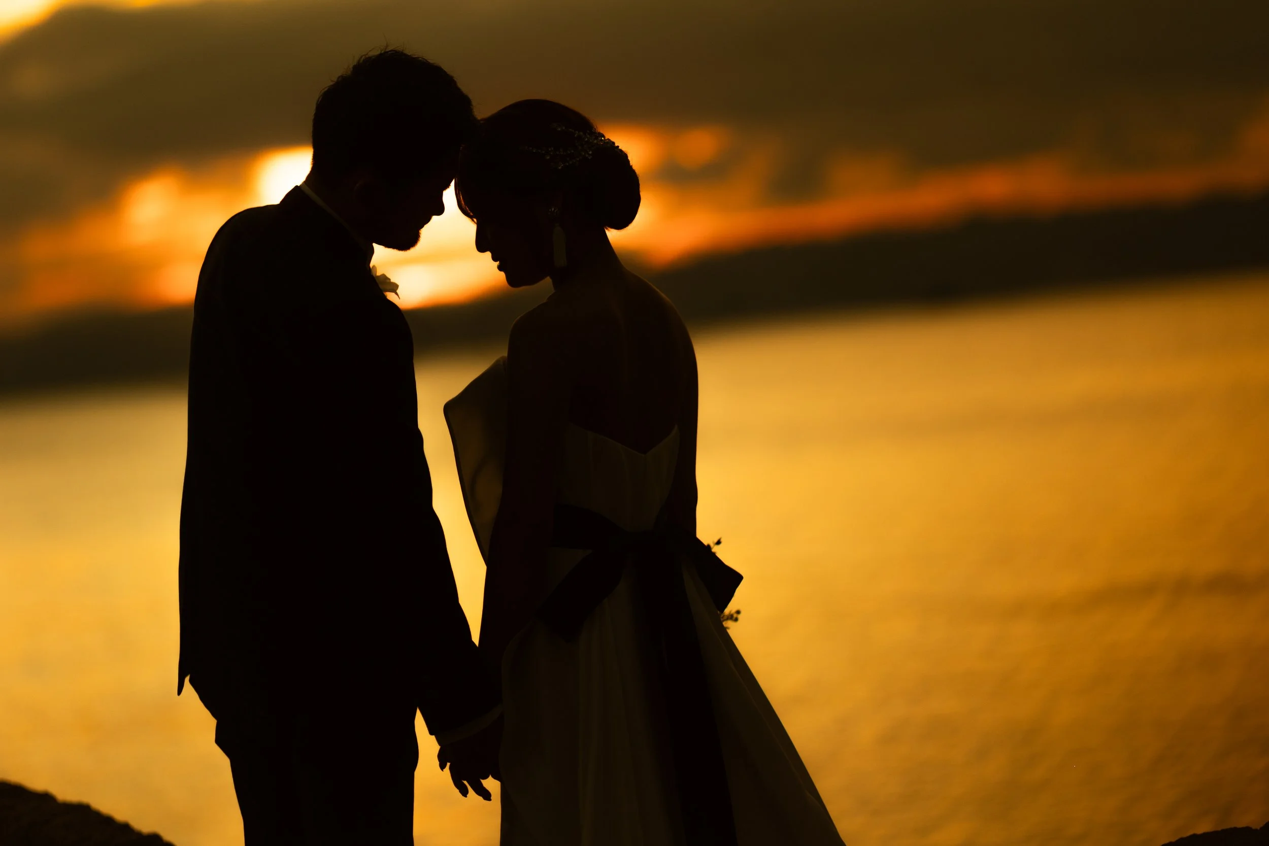 ロケ撮影イメージ | 江田島 入鹿海岸 | 夕焼けの海辺で手を取り合うカップルのシルエット