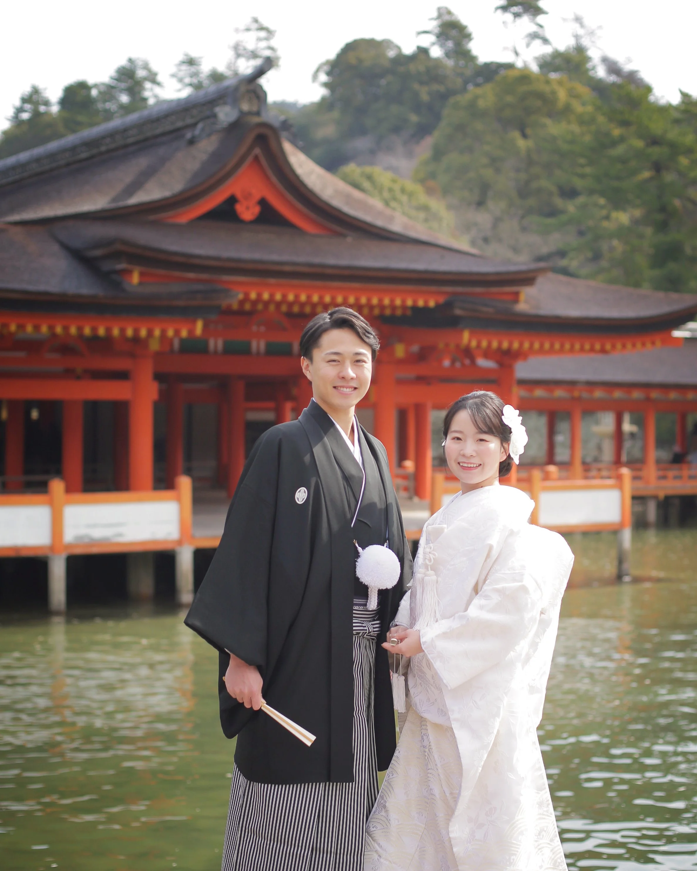 TOPページ　宮島エリアキャッチ画像｜嚴島神社社殿を背景にする新郎新婦