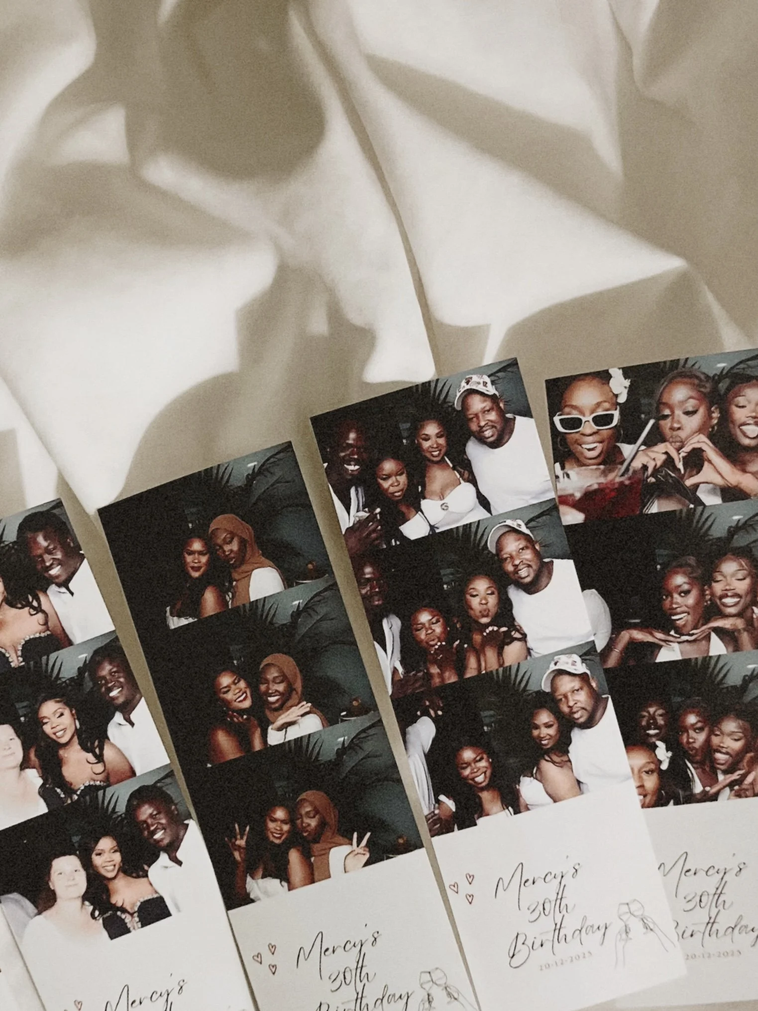 Photo booth strips with group photos of friends celebrating Mercy's 30th birthday, dated 10-12-2023, on a white table.