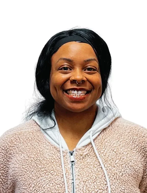 A woman with dark hair, smiling, wearing a light-colored fleece jacket and a black headband against a plain white background.