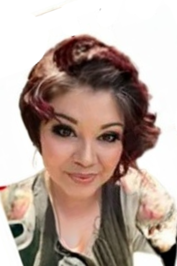 A woman with short, wavy dark hair with red highlights, wearing makeup, a floral top, and a dark vest.