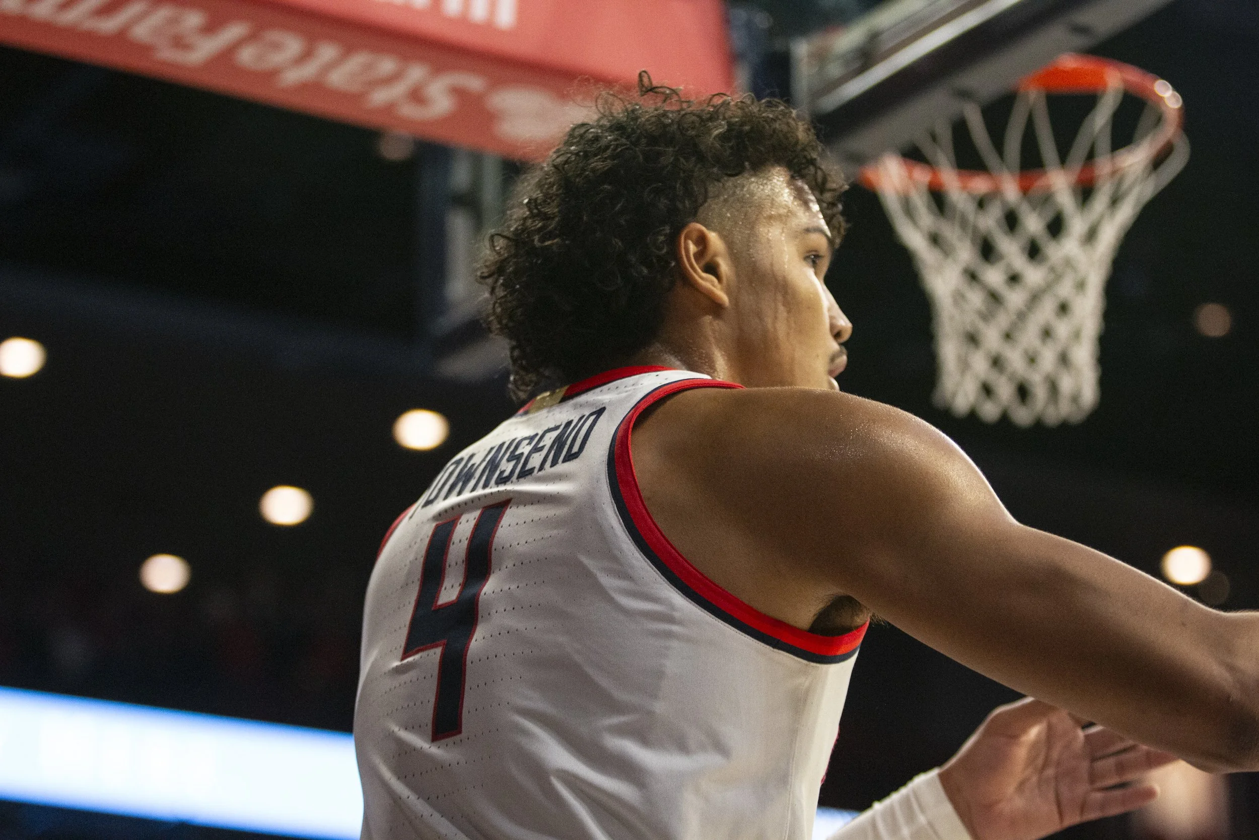 A basketball player wearing a white jersey with red and black details, number 4, is preparing to shoot a basketball near the hoop.