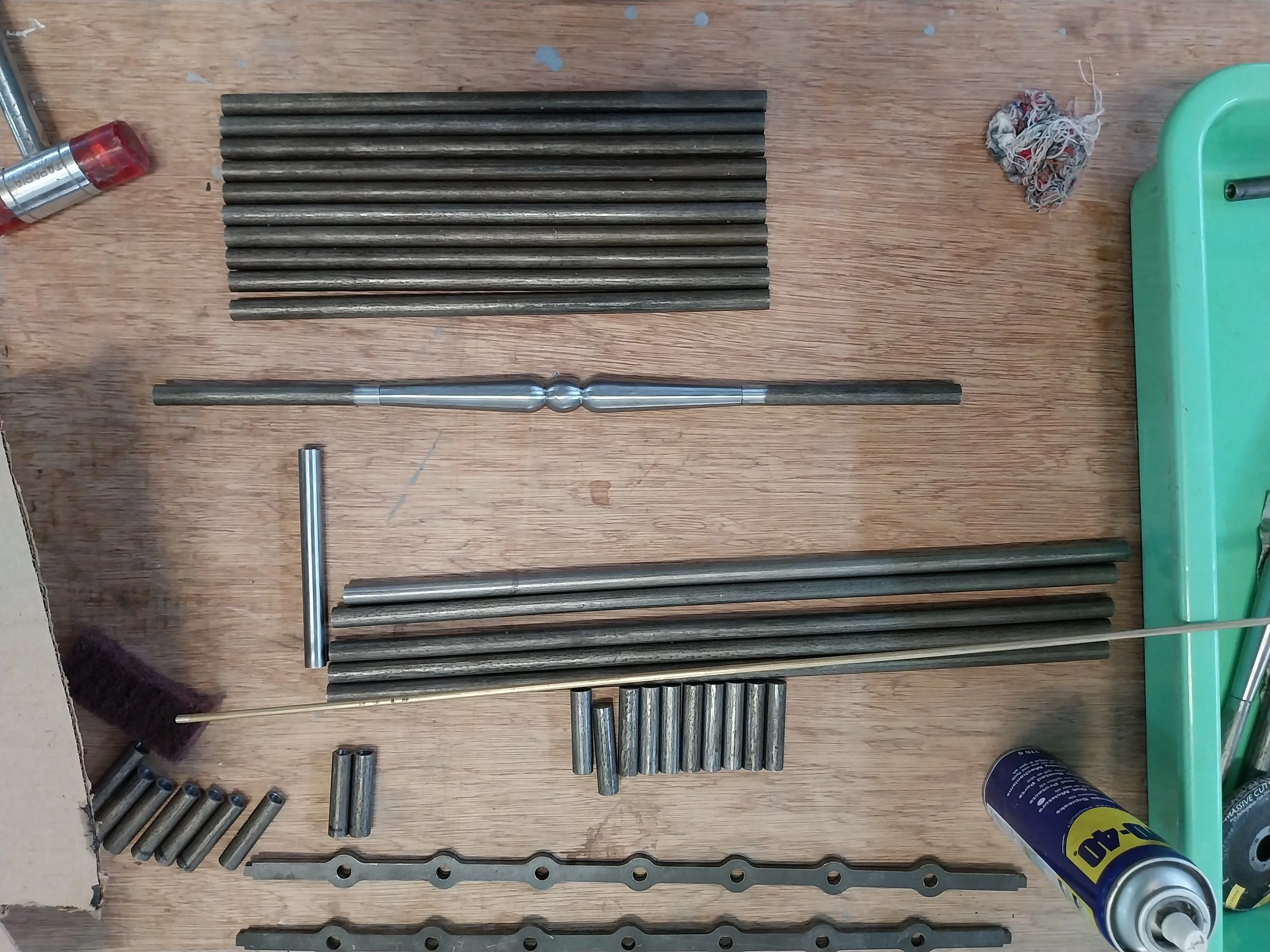 Metal rods, tools, and small parts arranged on a wooden work surface.