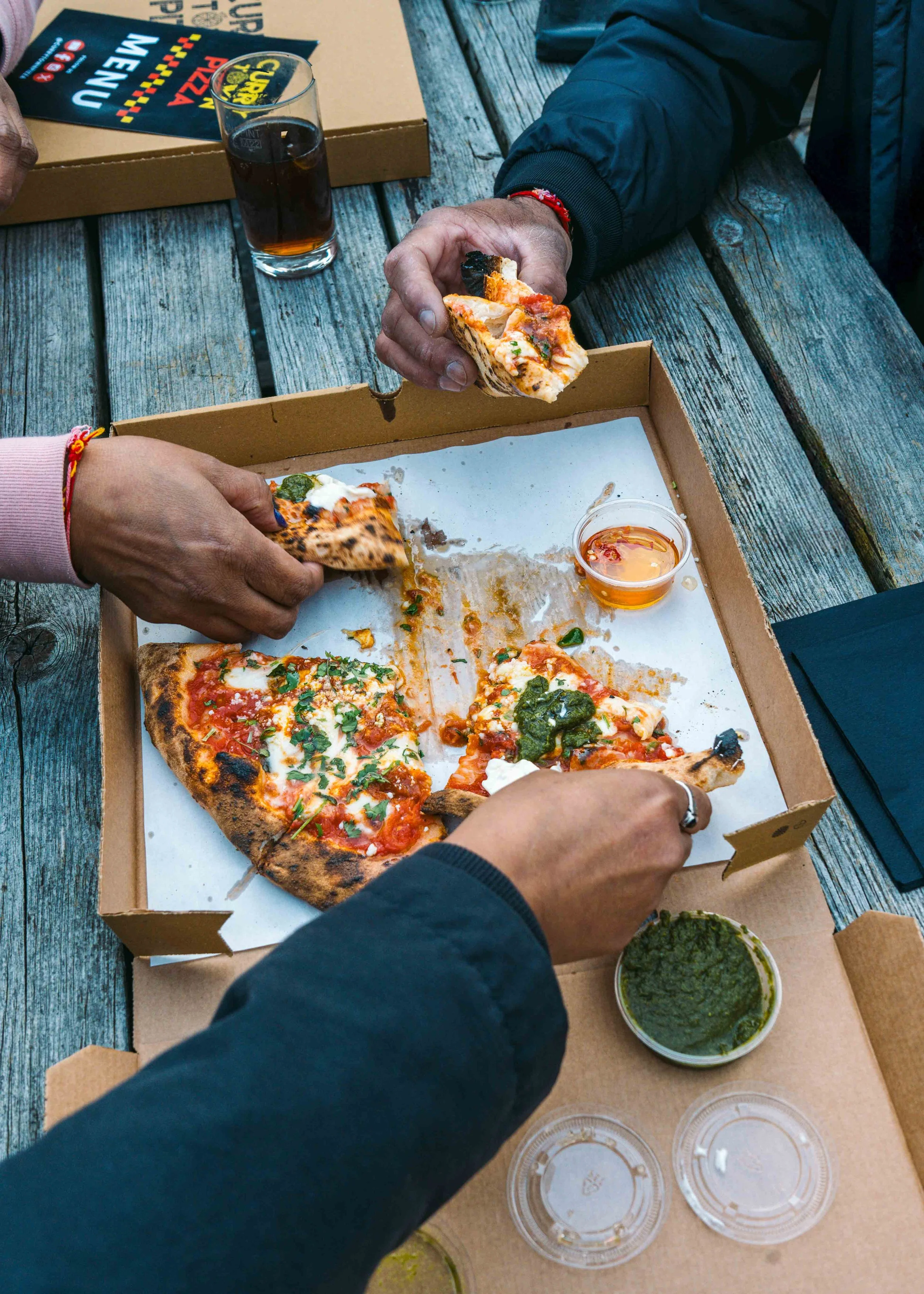 Groups of people sharing a Mumbai Margherita fusion pizza from Curry Town, featuring coriander pesto and fresh toppings, ordered for takeaway or delivery in Crawley