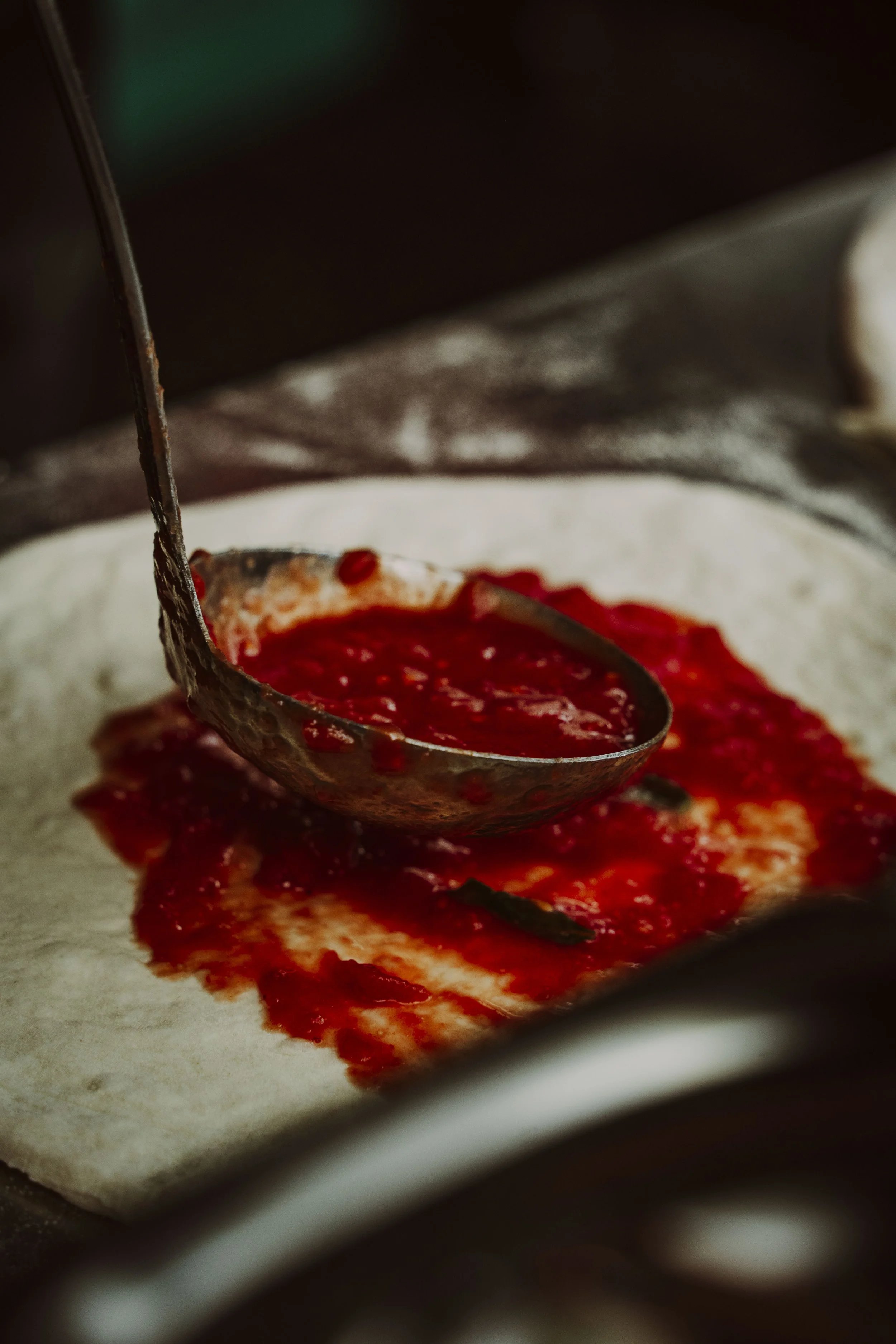 Spreading fresh tomato sauce on an authentic stonebaked pizza base at Curry Town Pizza Crawley