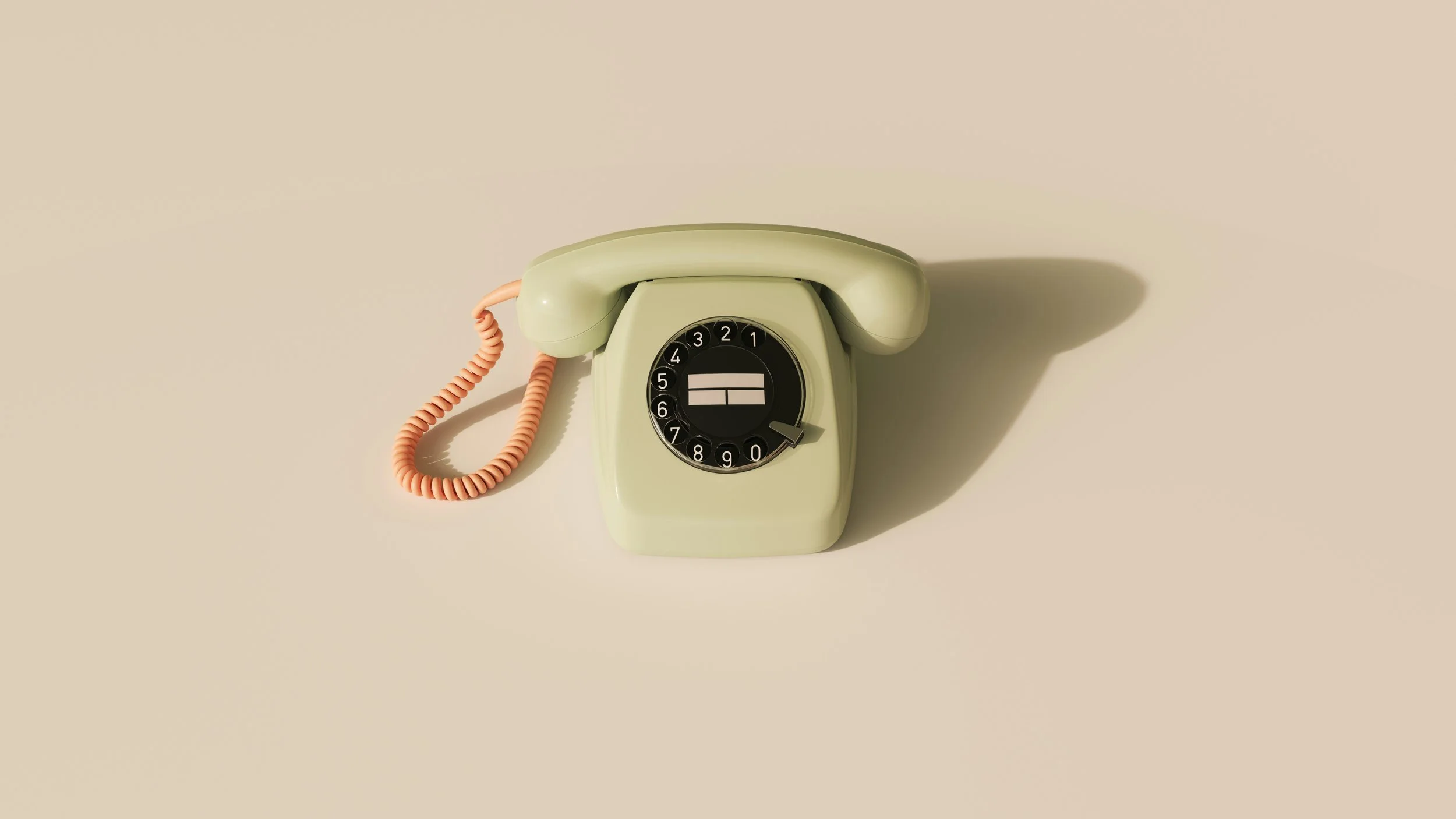 A vintage rotary dial telephone in light green with a orange coiled cord, placed on a beige surface with a shadow cast to the right.