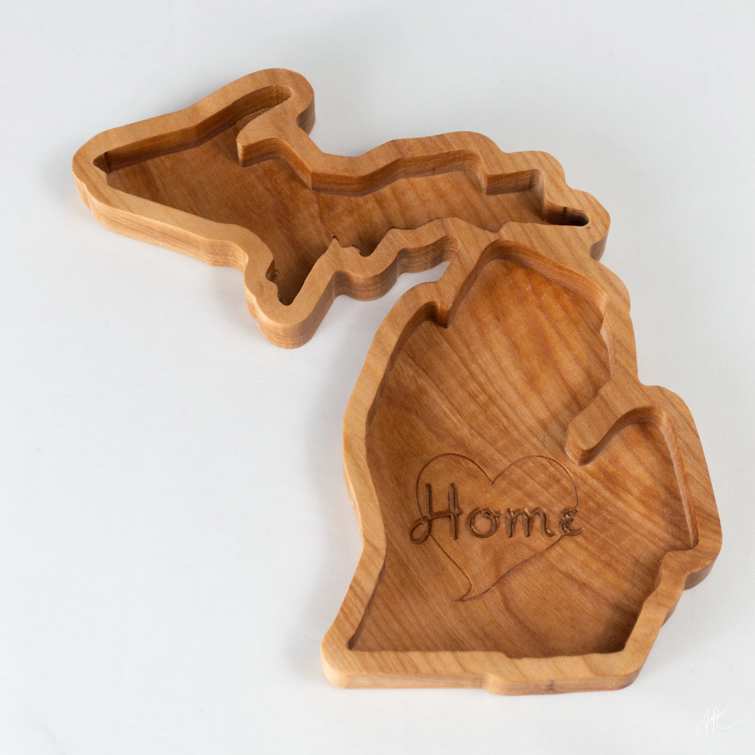 Two wooden Texas-shaped cookie cutters on a white surface, one with the word 'Home' inscribed inside a heart.
