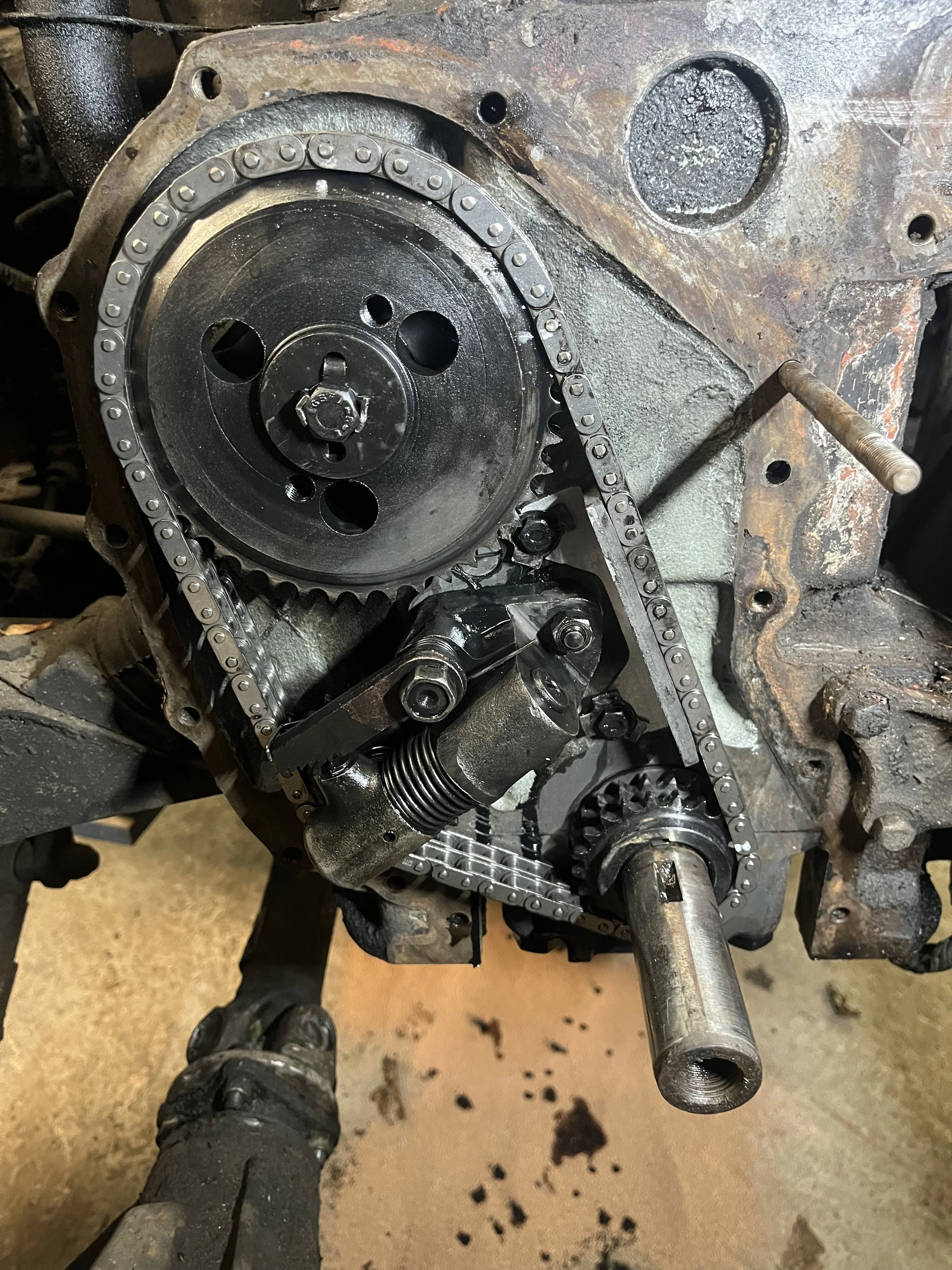 Close-up van een motor met een distributieketting, distributietandwielen en een gemonteerde waterpompconstructie.