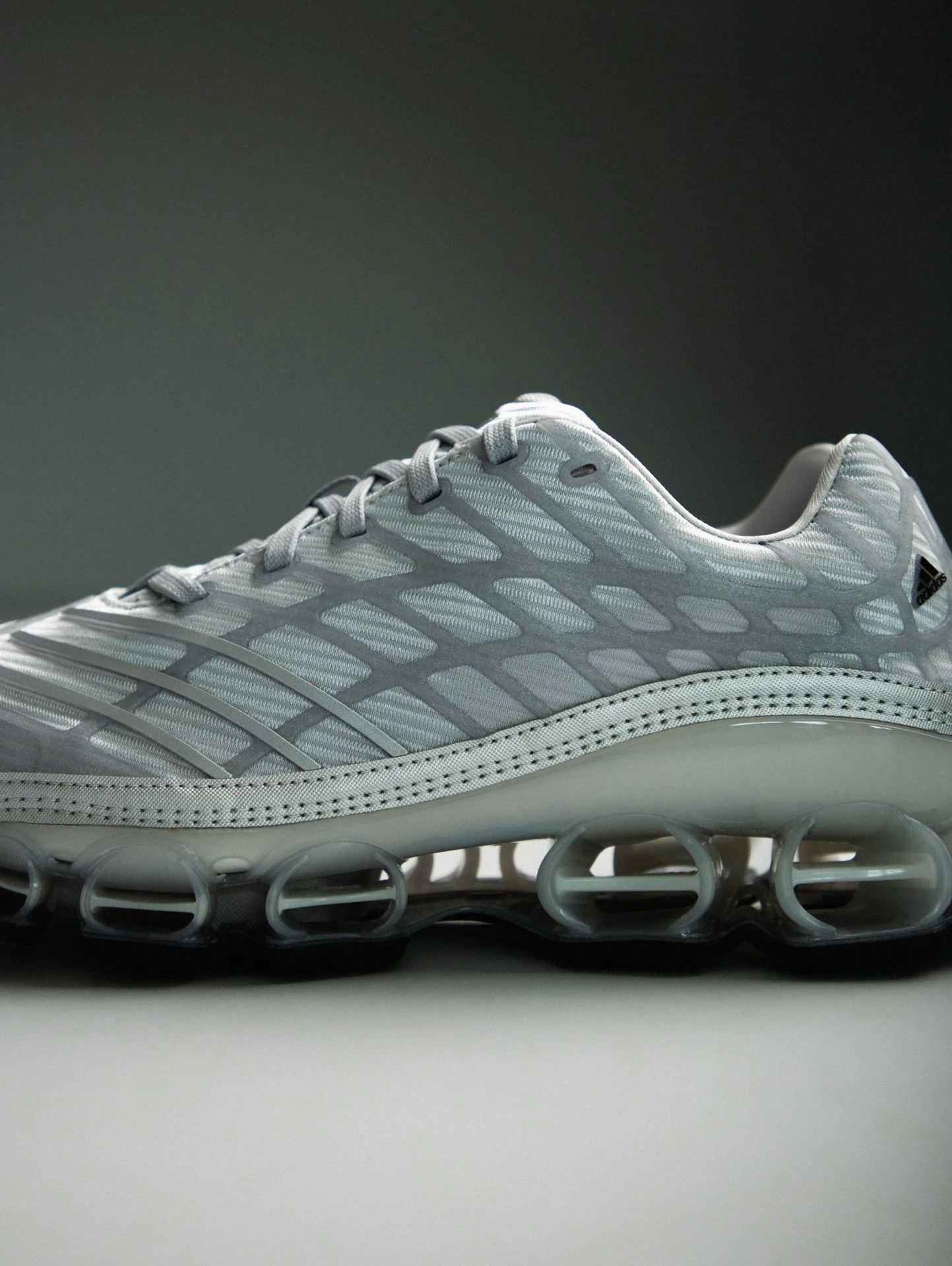 Weißer Adidas Sportschuh mit aerogelähnlicher Sohle auf grauem Hintergrund.