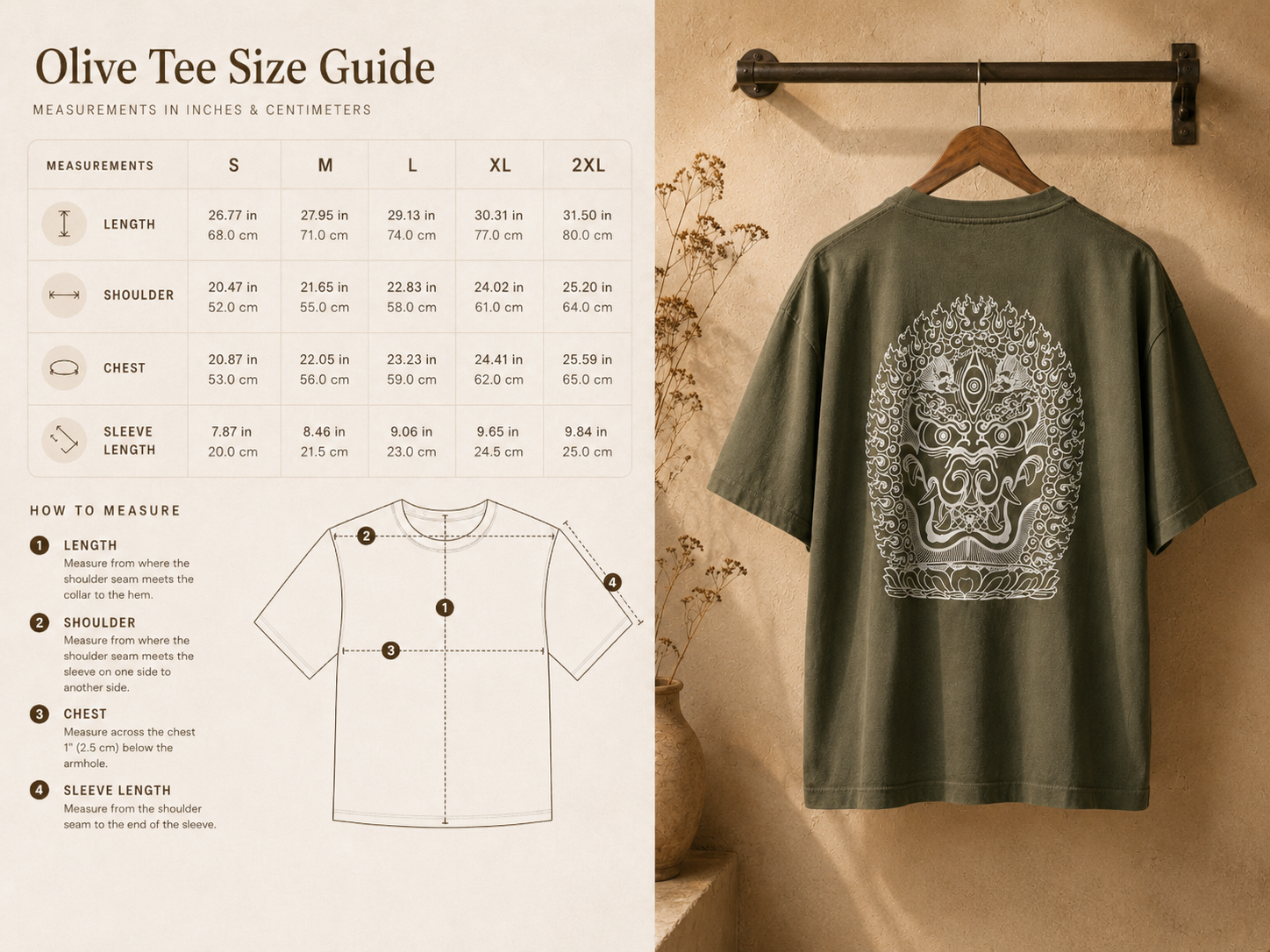 Olive green t-shirt hanging on a wooden hanger on a black metal clothing rod, with a white intricate mask or face design on the back, next to a beige wall and a decorative vase with dried flowers.