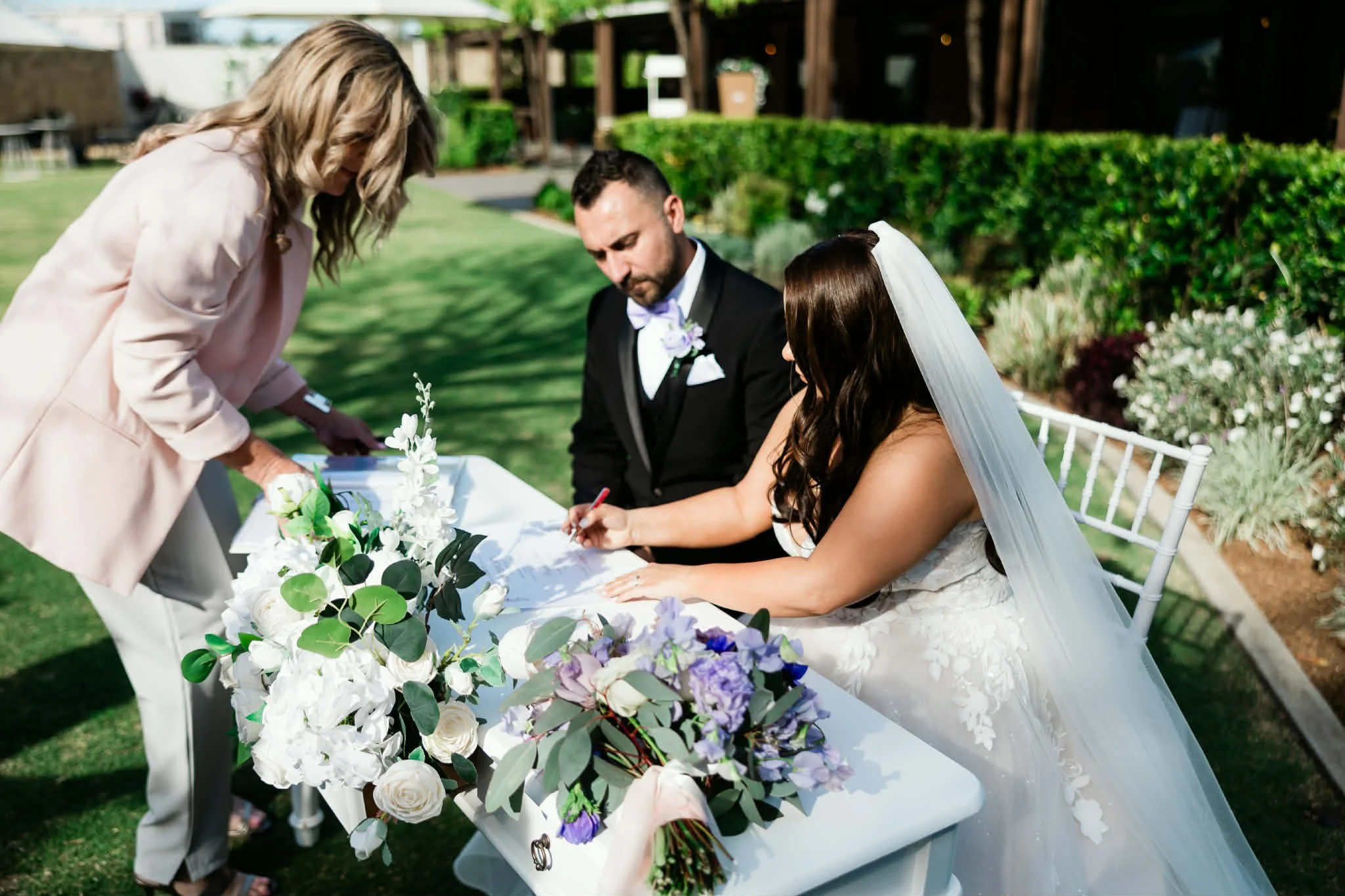Laurie’s customers, Mariana and Carmen holding hands on a green lawn on their wedding day.