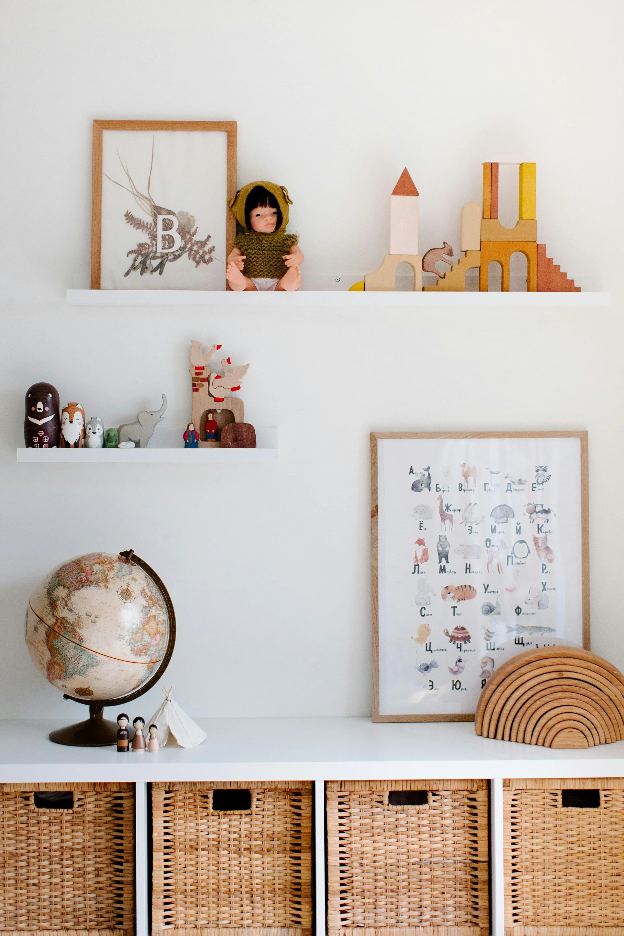 Decorative shelves in a children's playroom with wooden toys, framed artwork, a globe, and small figurines.