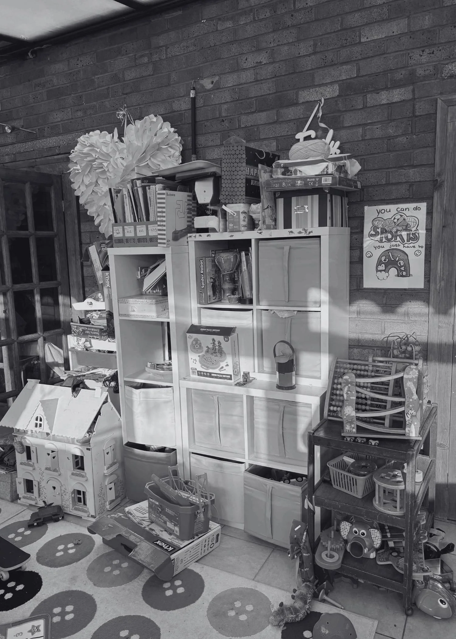 A messy children's playroom with toys on top of and spilling out of square wooden storage containers and pull out drawers.