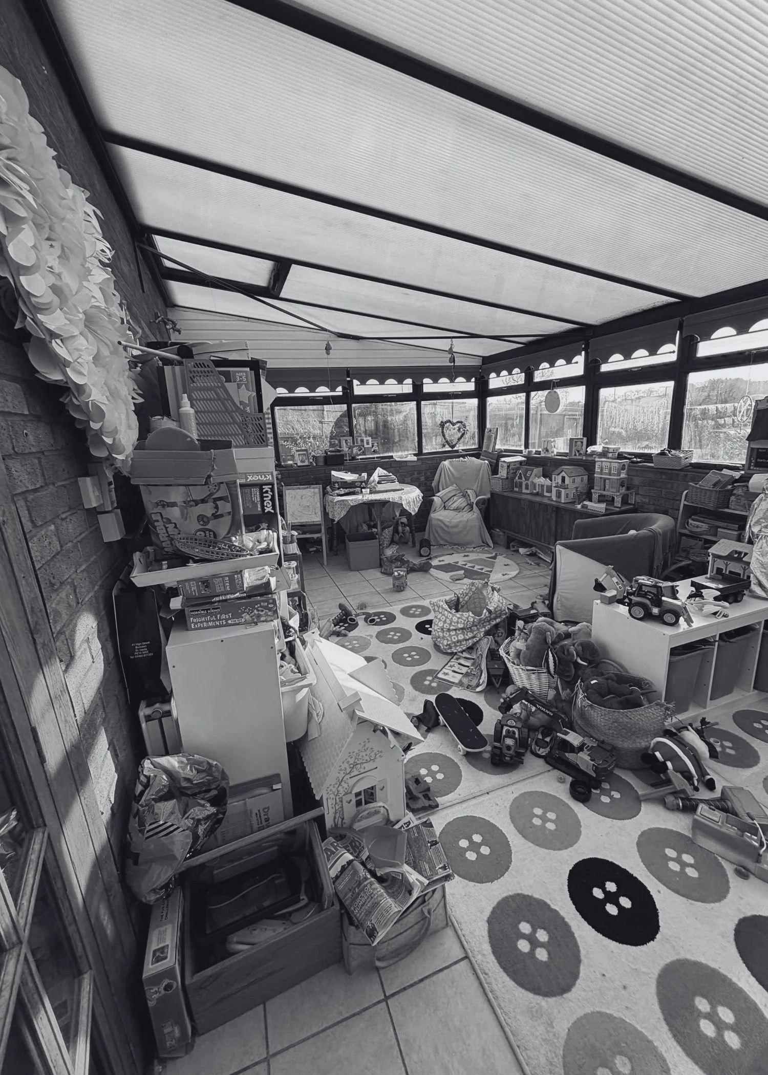 A messy children's playroom with storage units, armchairs and a table. The toys spill out of the storage units and across the floor.