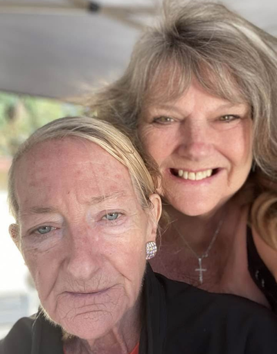 Two women taking a selfie outdoors, smiling at the camera.