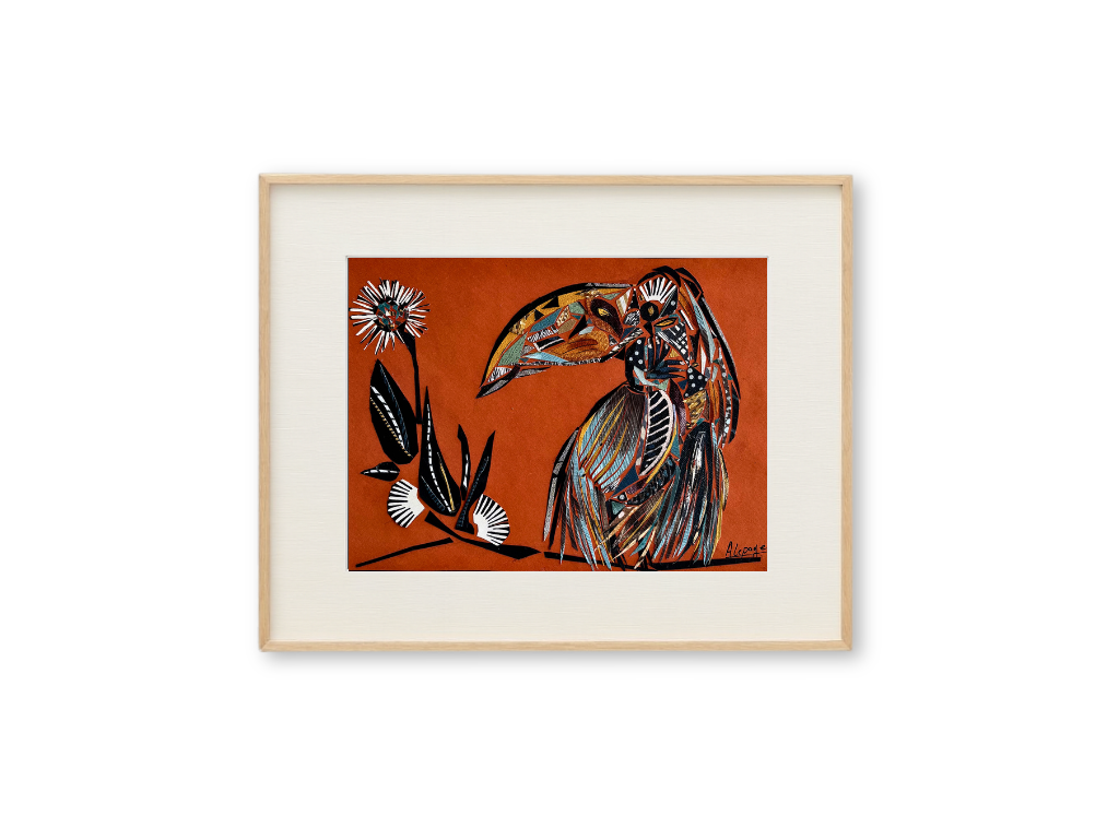 Un collage représentant un toucan stylisé avec un fond orange, encadrée dans un cadre en bois.
