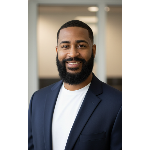 Professional man smiling, wearing a dark suit jacket and white shirt, in an office setting