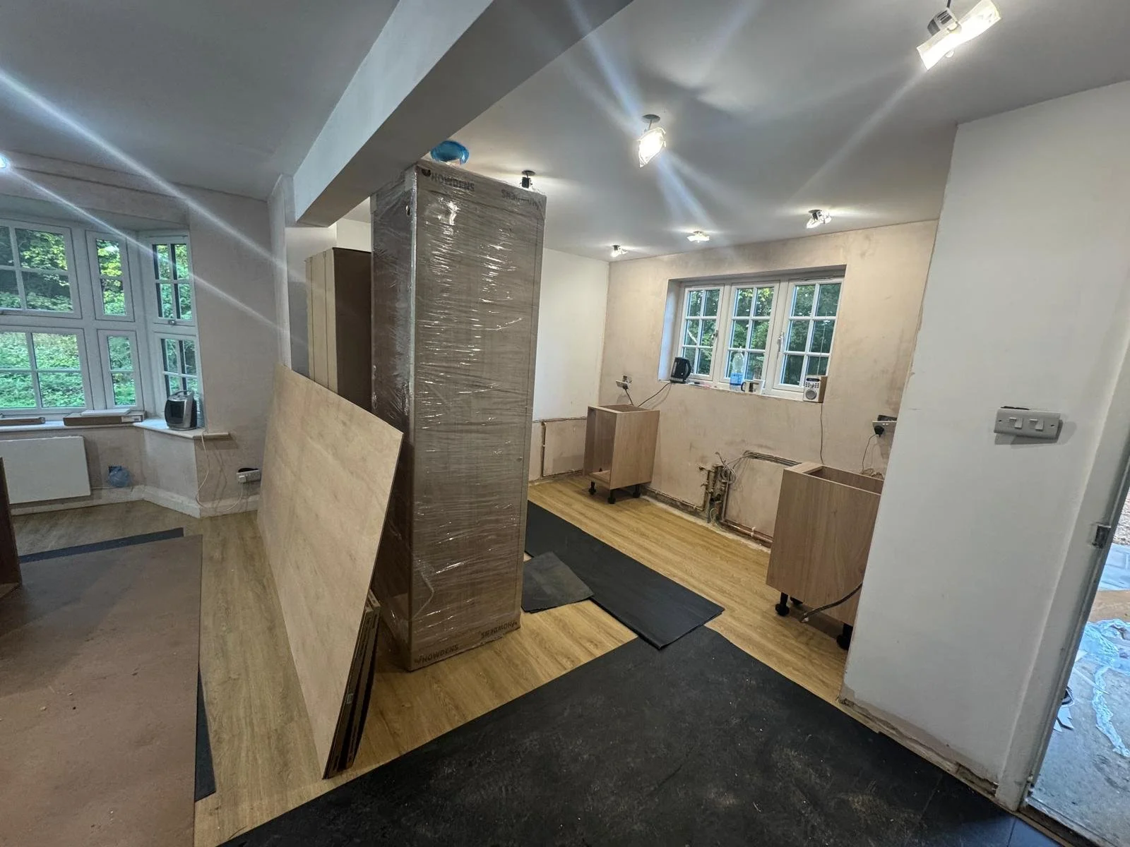 Interior of a room under renovation with construction materials, wooden cabinets, and tile flooring.