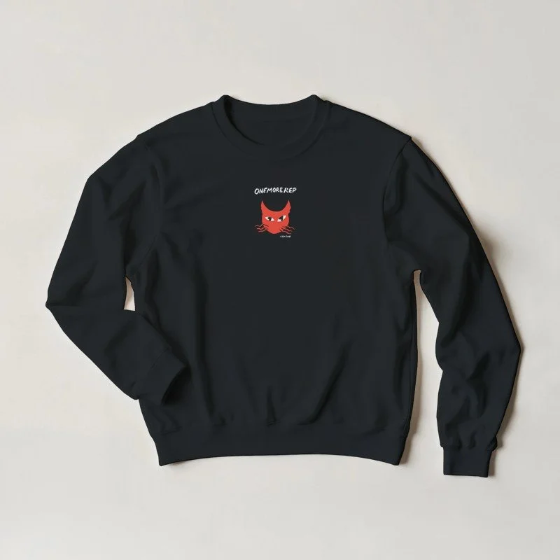 Sweatshirt noir avec un dessin d'un chat rouge aux yeux jaunes et le texte 'ONEMORE REP' au-dessus.