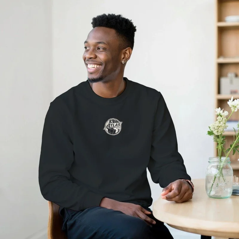 Un jeune homme souriant assis à une table avec une plante en verre à côté.