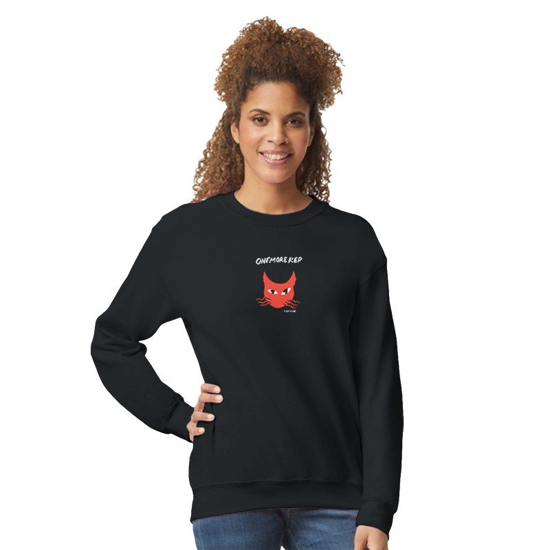 Femme souriante portant un sweat noir avec un dessin de chat rouge et le texte 'ONEMORE.REP'.