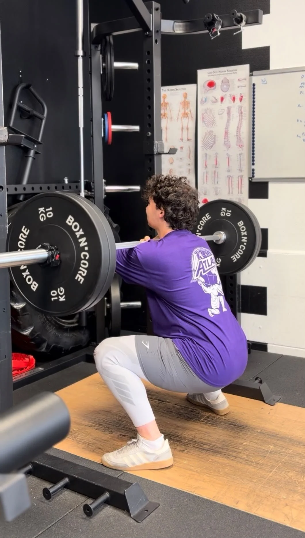Une personne en train de faire un squat avec une barre lourde dans une salle de sport.