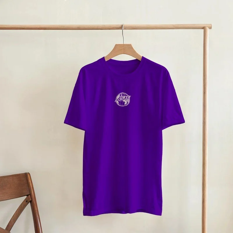 Un t-shirt violet suspendu à une barre en bois, avec un logo 'Atlas' au centre.