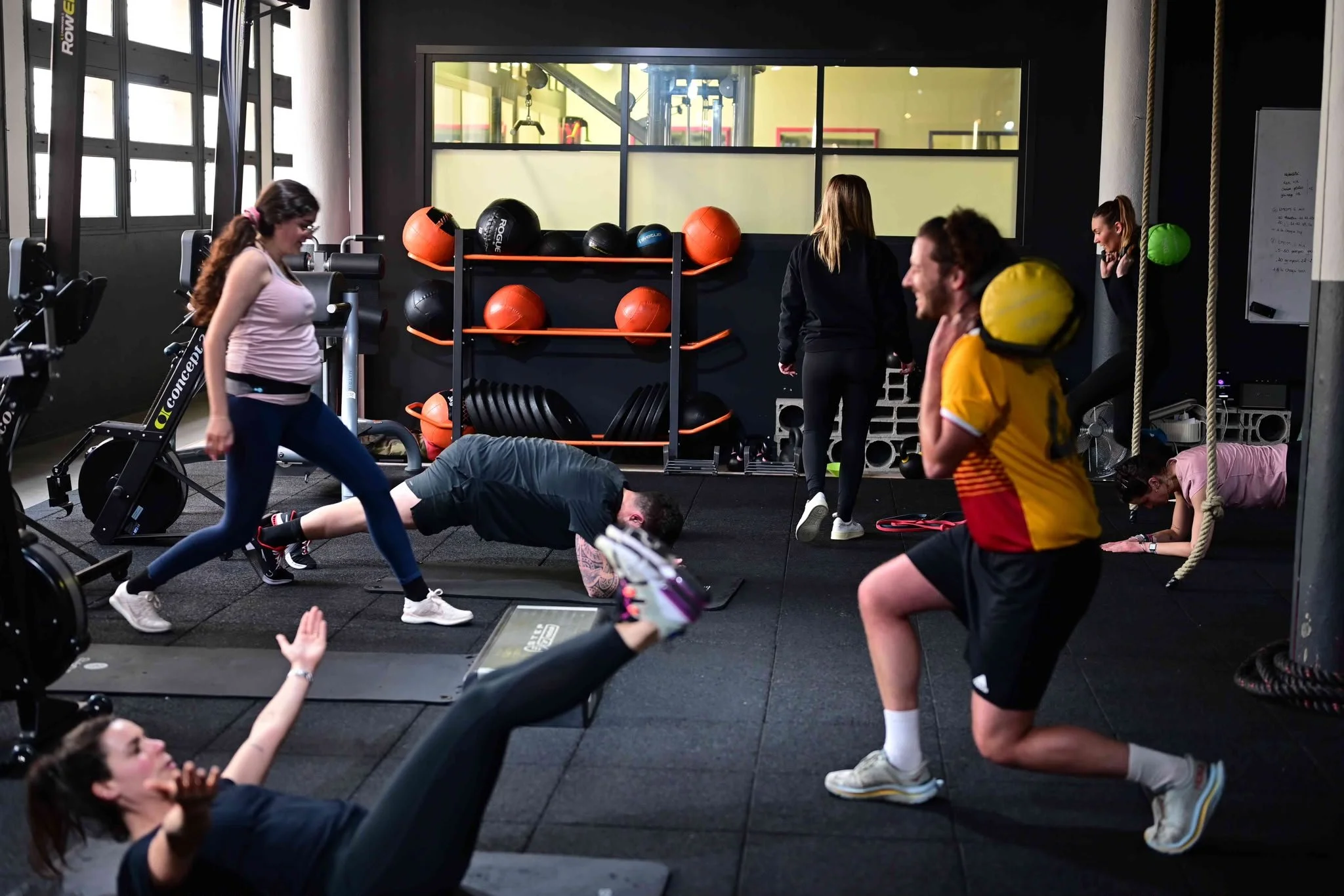 Groupe de personnes en salle de sport effectuant différents exercices de fitness et de musculation.
