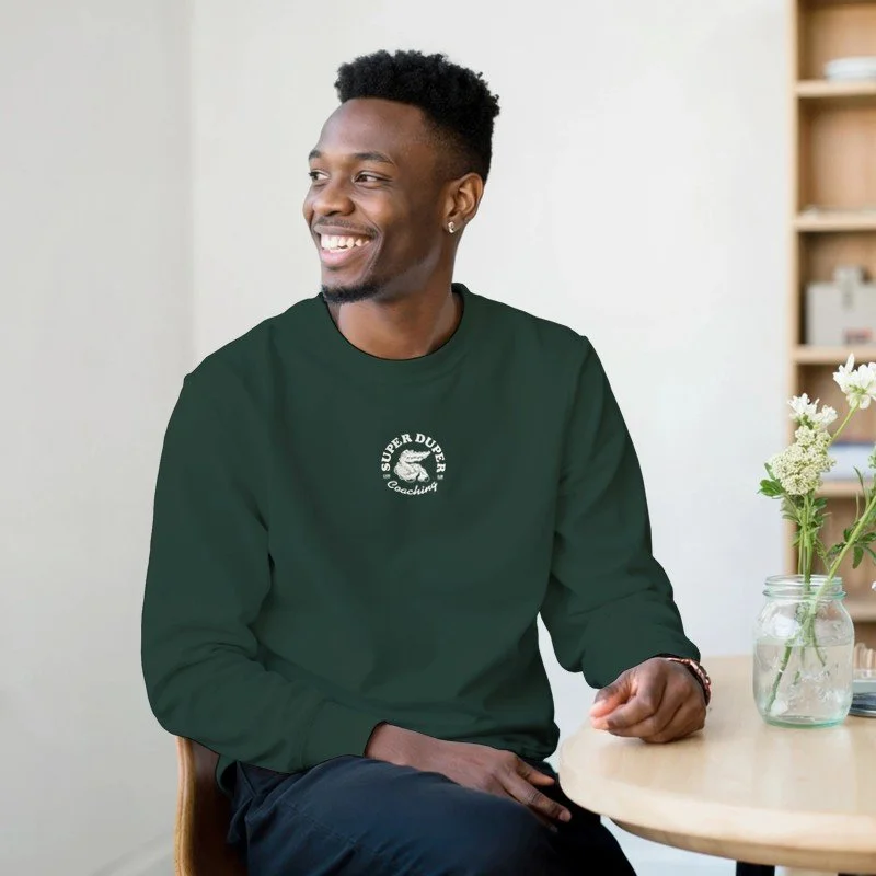 Jeune homme souriant assis à une table avec une vase de fleurs.