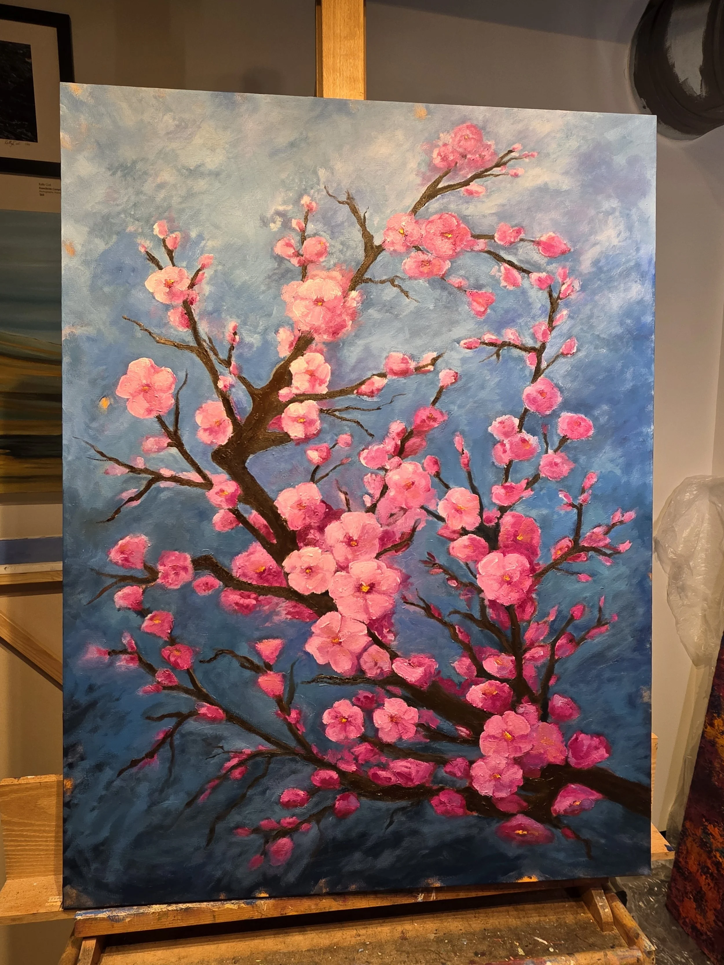 A painting of pink cherry blossoms on dark tree branches against a blue sky background.