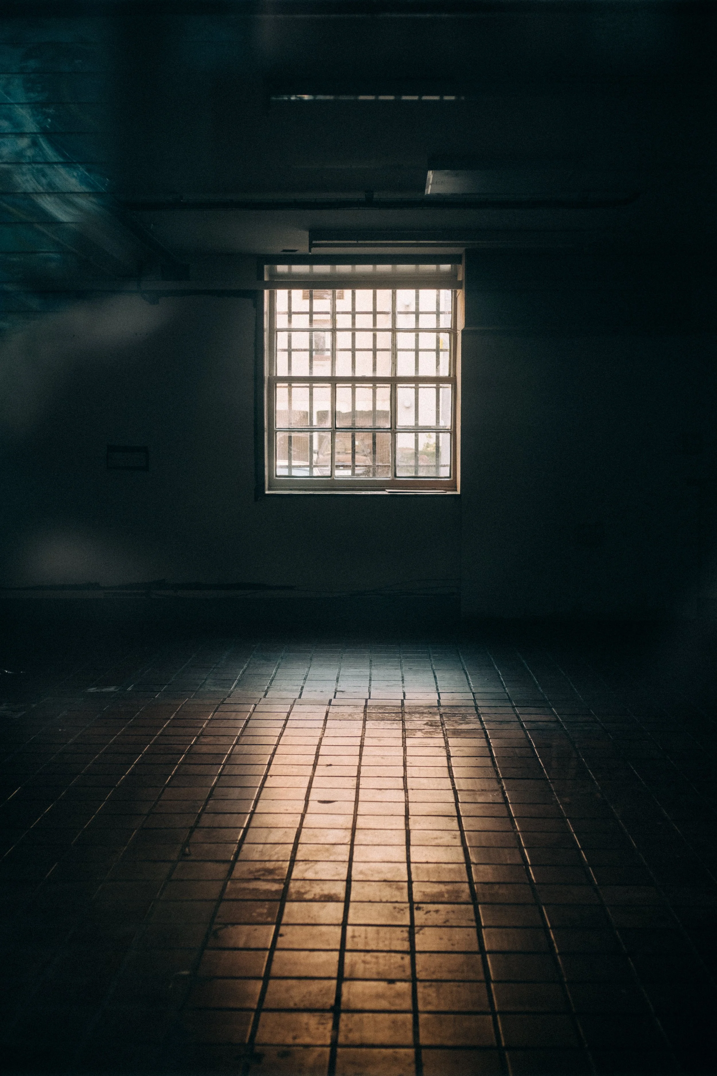 Light through a barred window reflecting on floor tiles